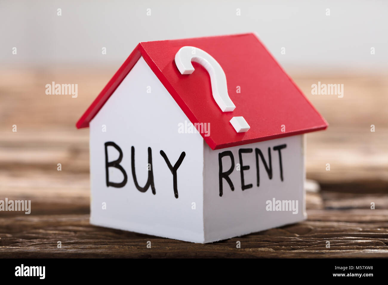 Closeup of buy or rent text with question mark on model house on wood Stock Photo