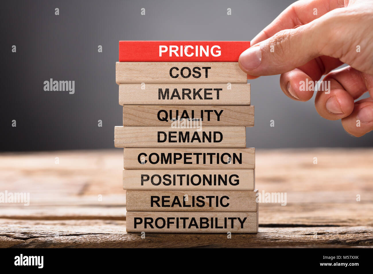 Closeup of hand building pricing concept with wooden blocks on wood Stock Photo