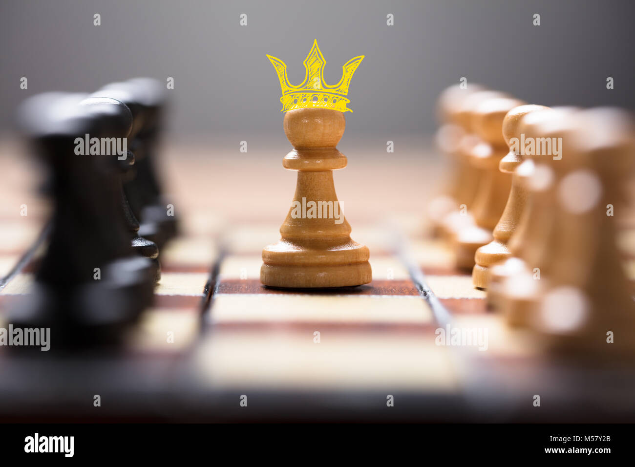 Closeup of pawn with king crown amidst chess pieces on board game