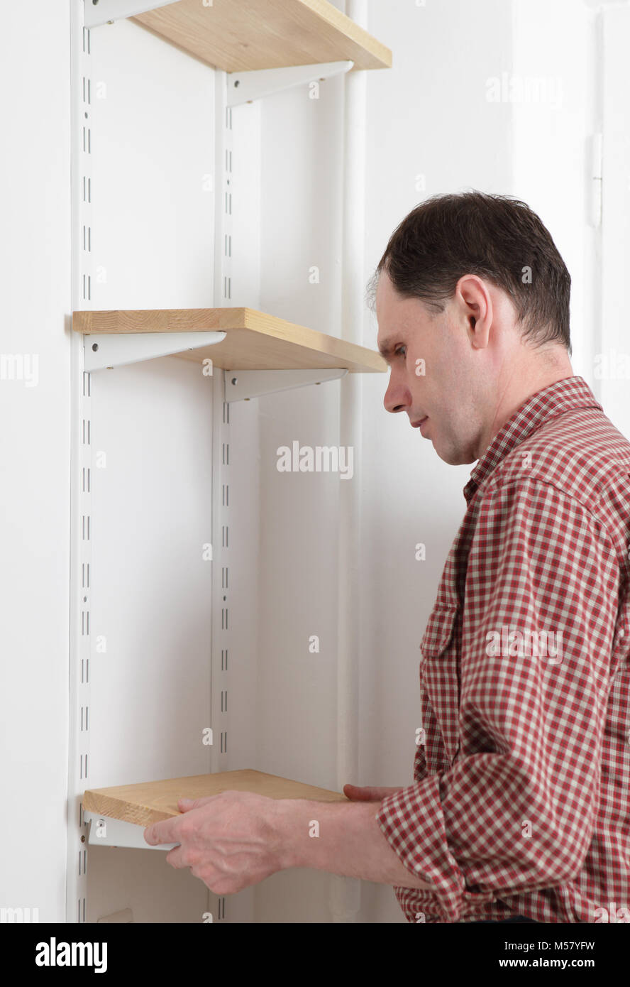 Man installing wooden shelves on brackets Stock Photo