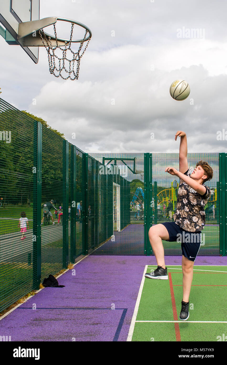 Young boy aged 13 plays basketball in Ballincollig Regional Park, County Cork, Ireland with copy space. Stock Photo