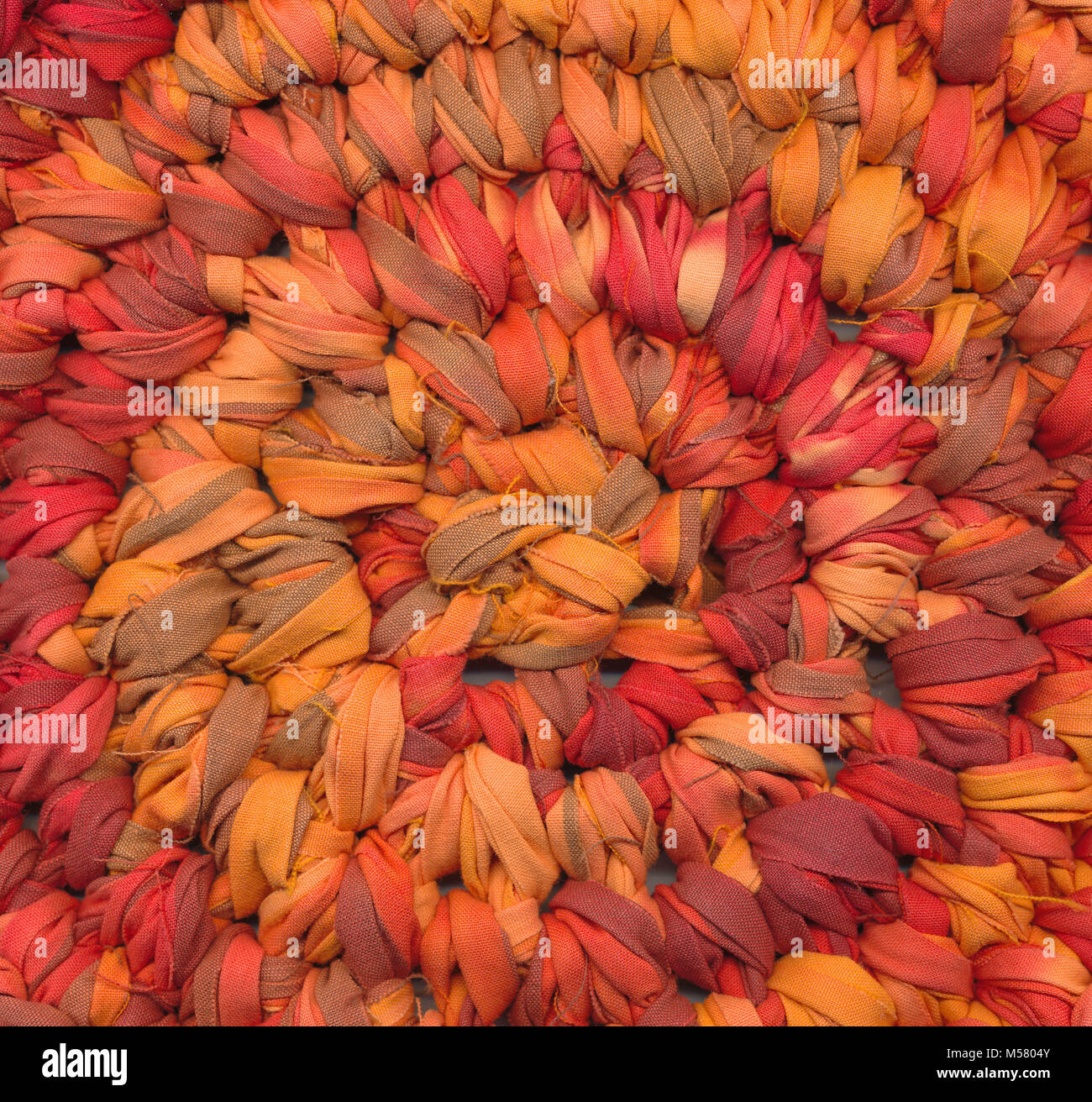 Closeup of crochet rag rug in red, orange and brown shades Stock Photo ...
