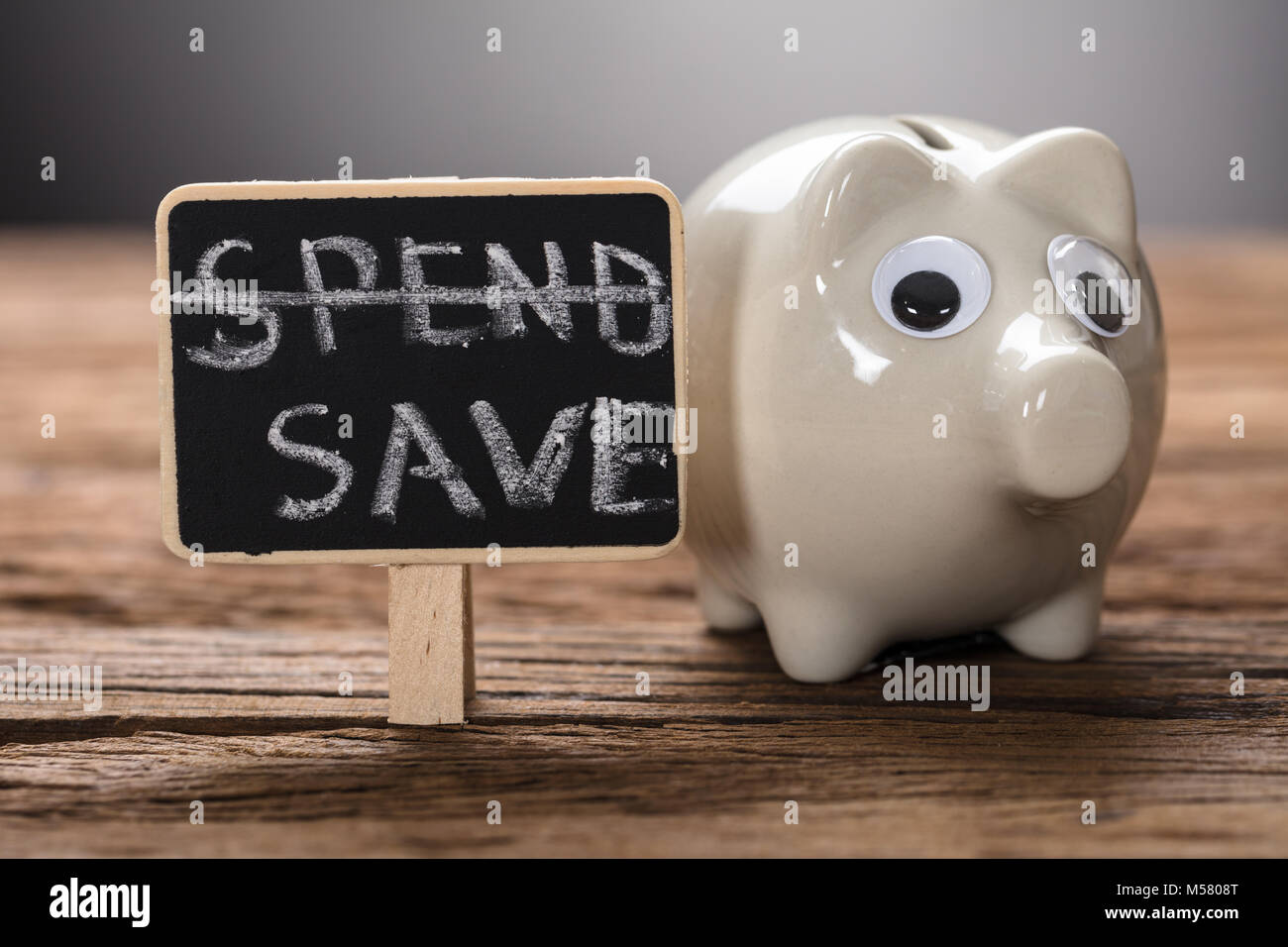 Closeup of piggybank by spend save sign on wood representing saving plan Stock Photo