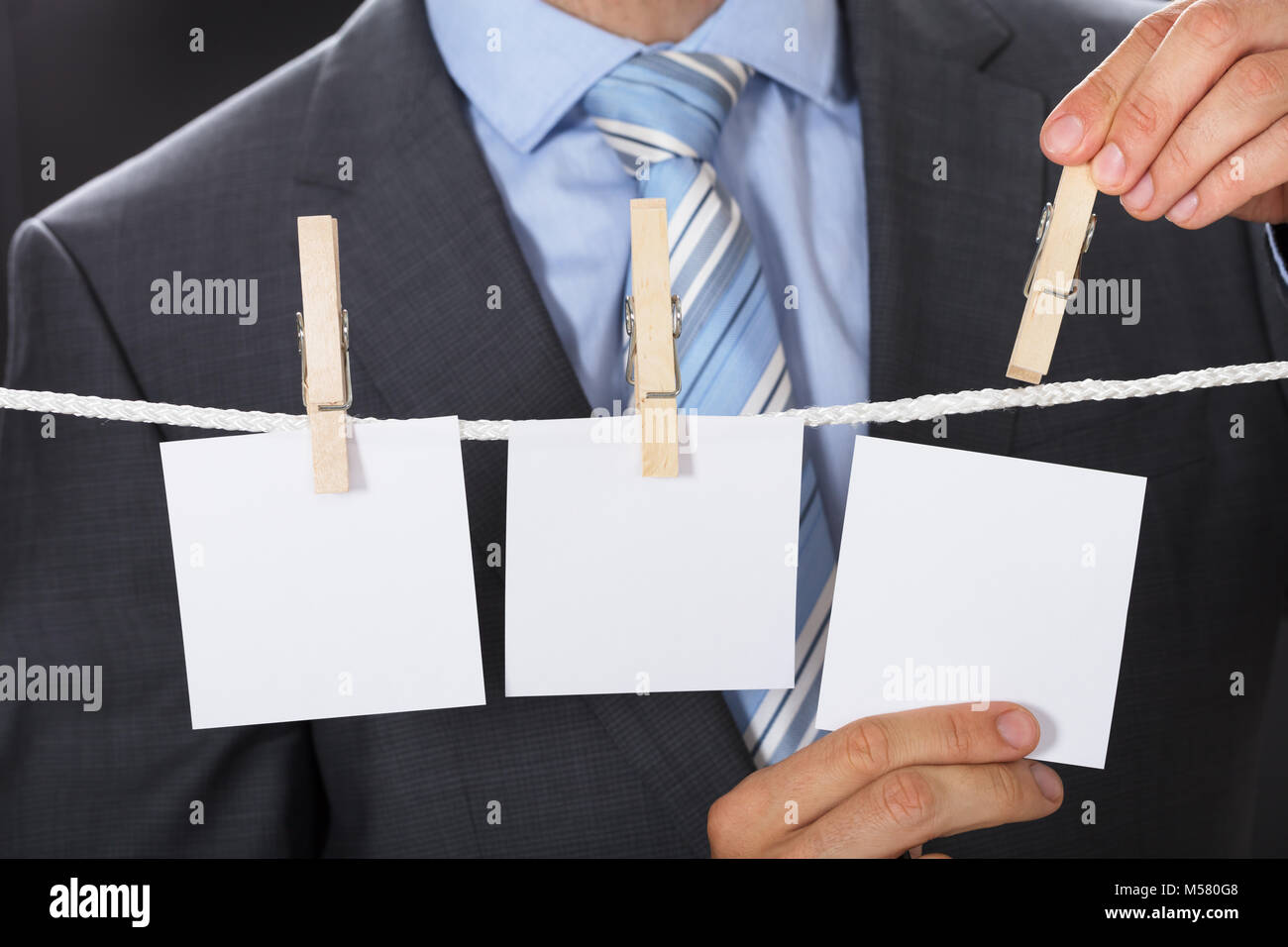 Closeup midsection of businessman pinning blank paper on clothesline Stock Photo