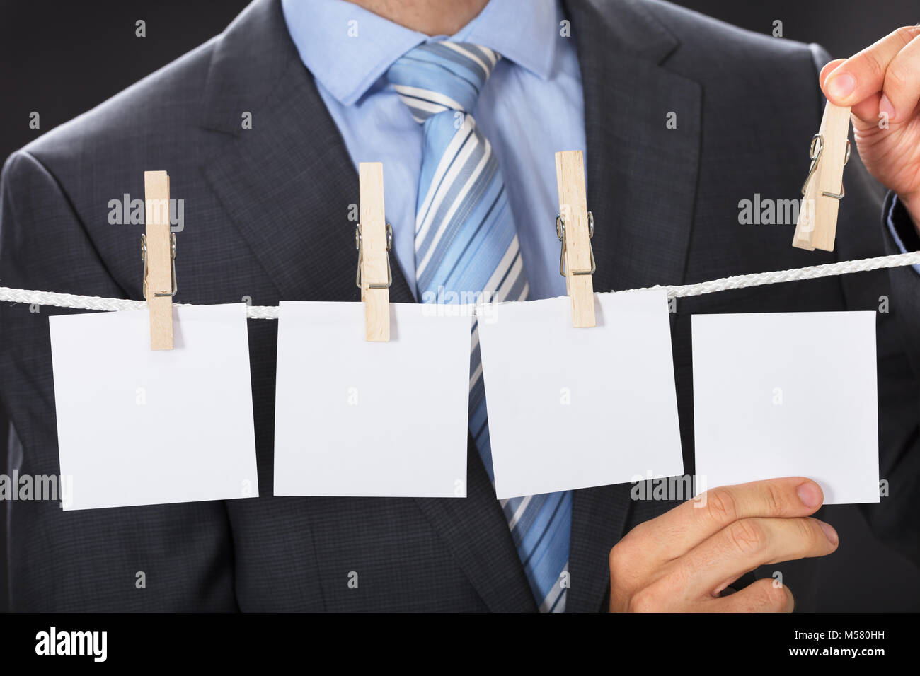 Closeup midsection of businessman pinning blank paper on clothesline Stock Photo