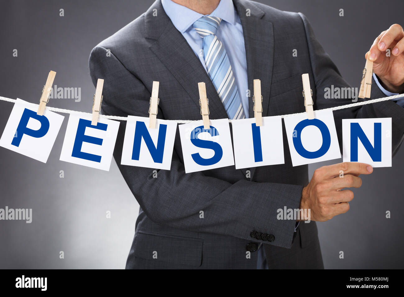 Closeup midsection of businessman pinning PENSION cards on clothesline Stock Photo