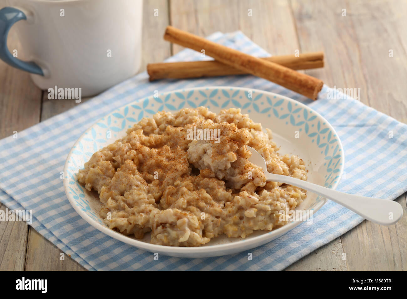 Oatmeal porridge with powdered cinnamon and cinnamon sticks Stock Photo