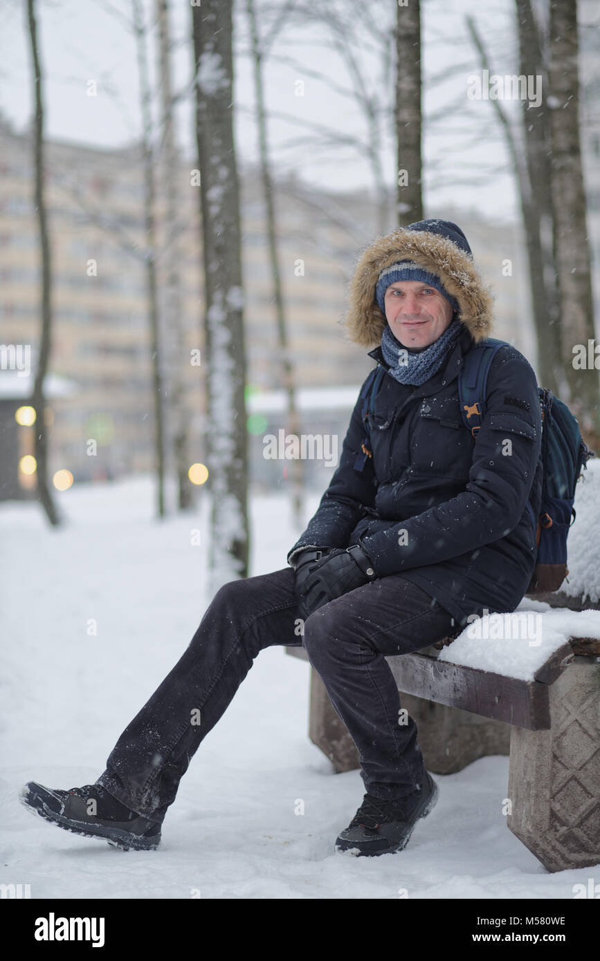 Man in winter clothing sitting on a bench Stock Photo