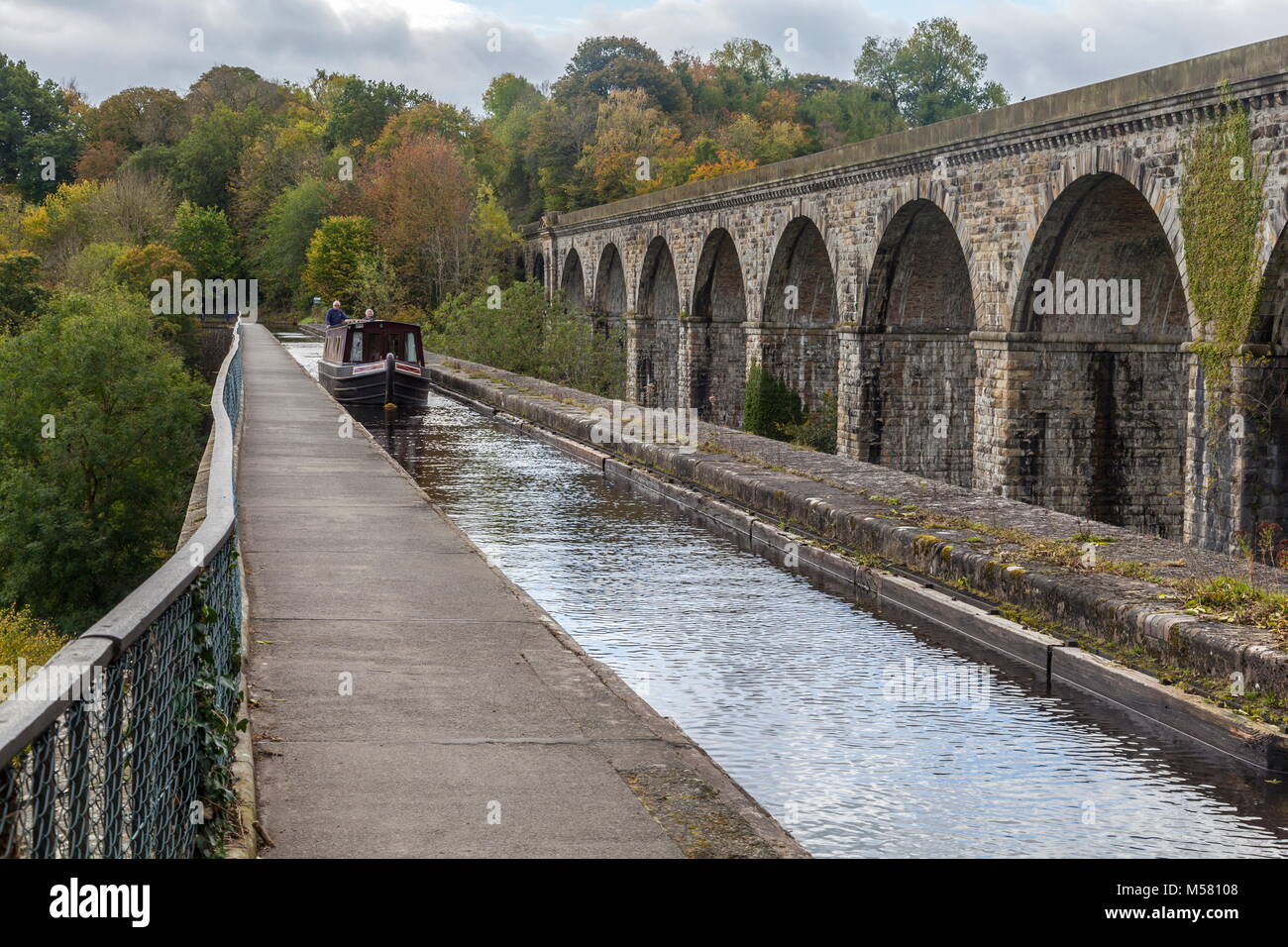 A narrow boat crosses from England into Wales across the Chirk Aqueduct during early Autumn. The Henry Robertson built Viaduct stands above the canal Stock Photo