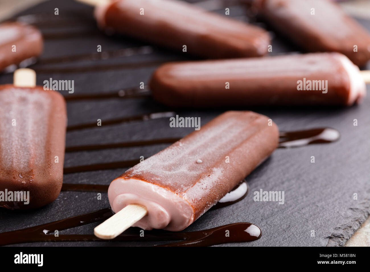 Ice cream bars coated with chocolate on a slate board Stock Photo