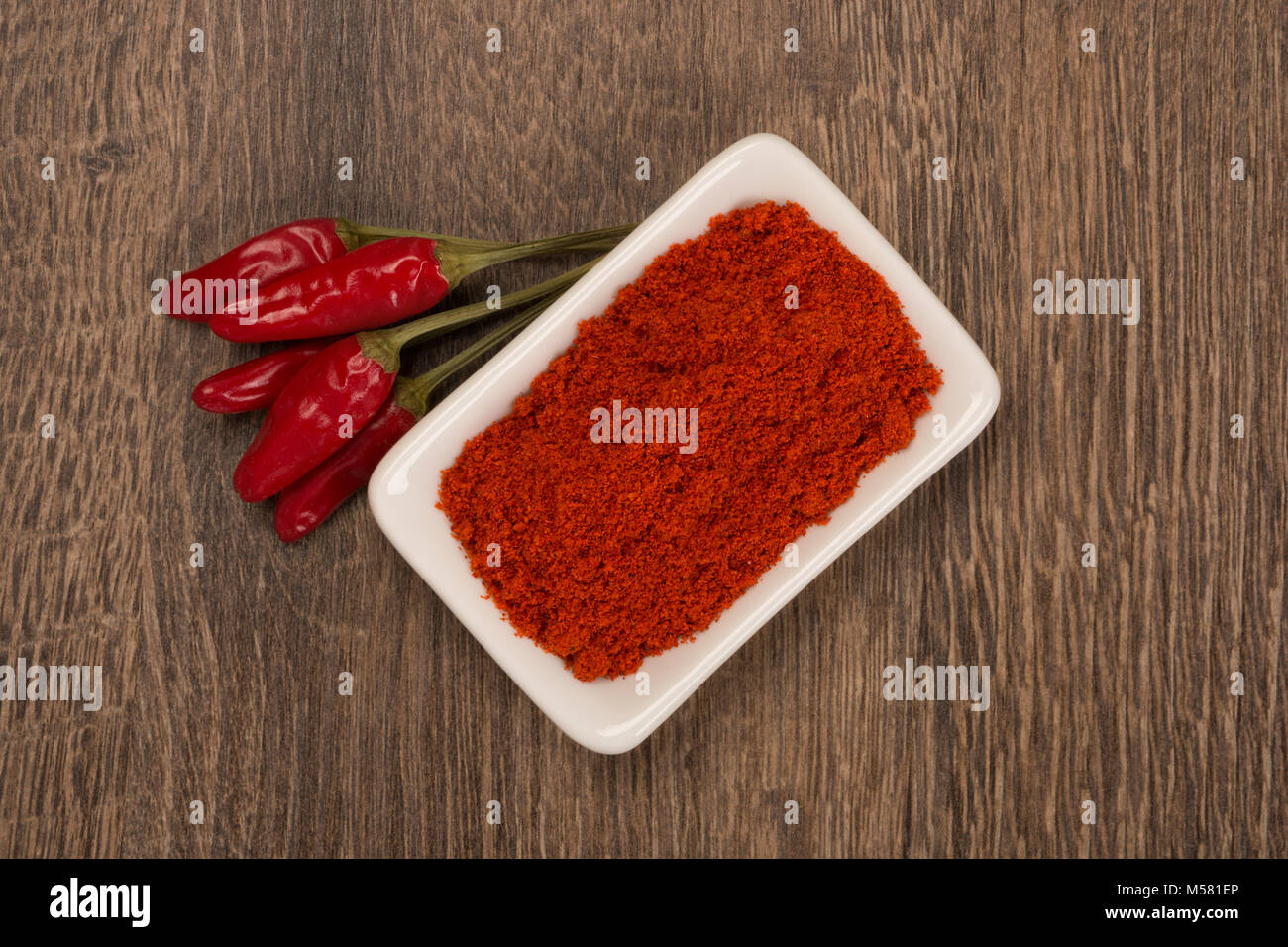 Ground and whole peppers on rustic wooden table. Stock Photo