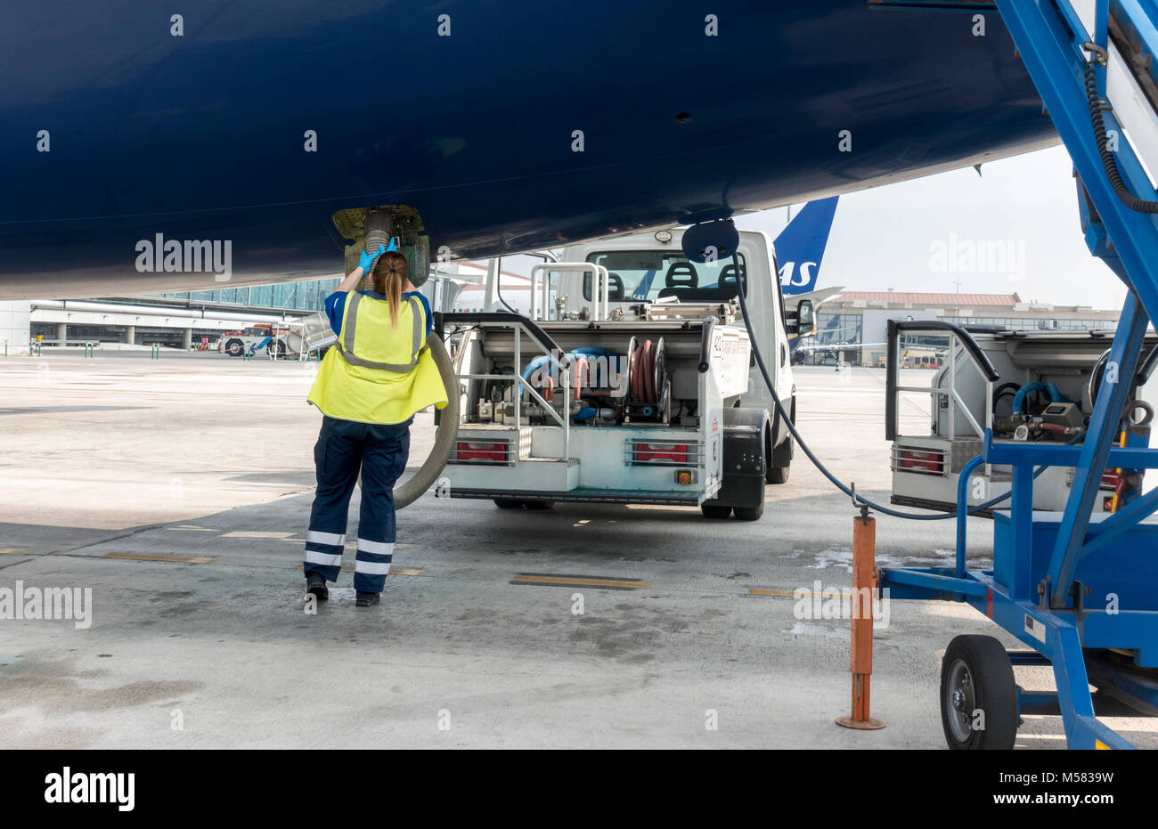 Female lav agent. Girl station attendant emptying a lavatory system of plane airplane aeroplane on tarmac. Woman ramper doing the lavs. Stock Photo