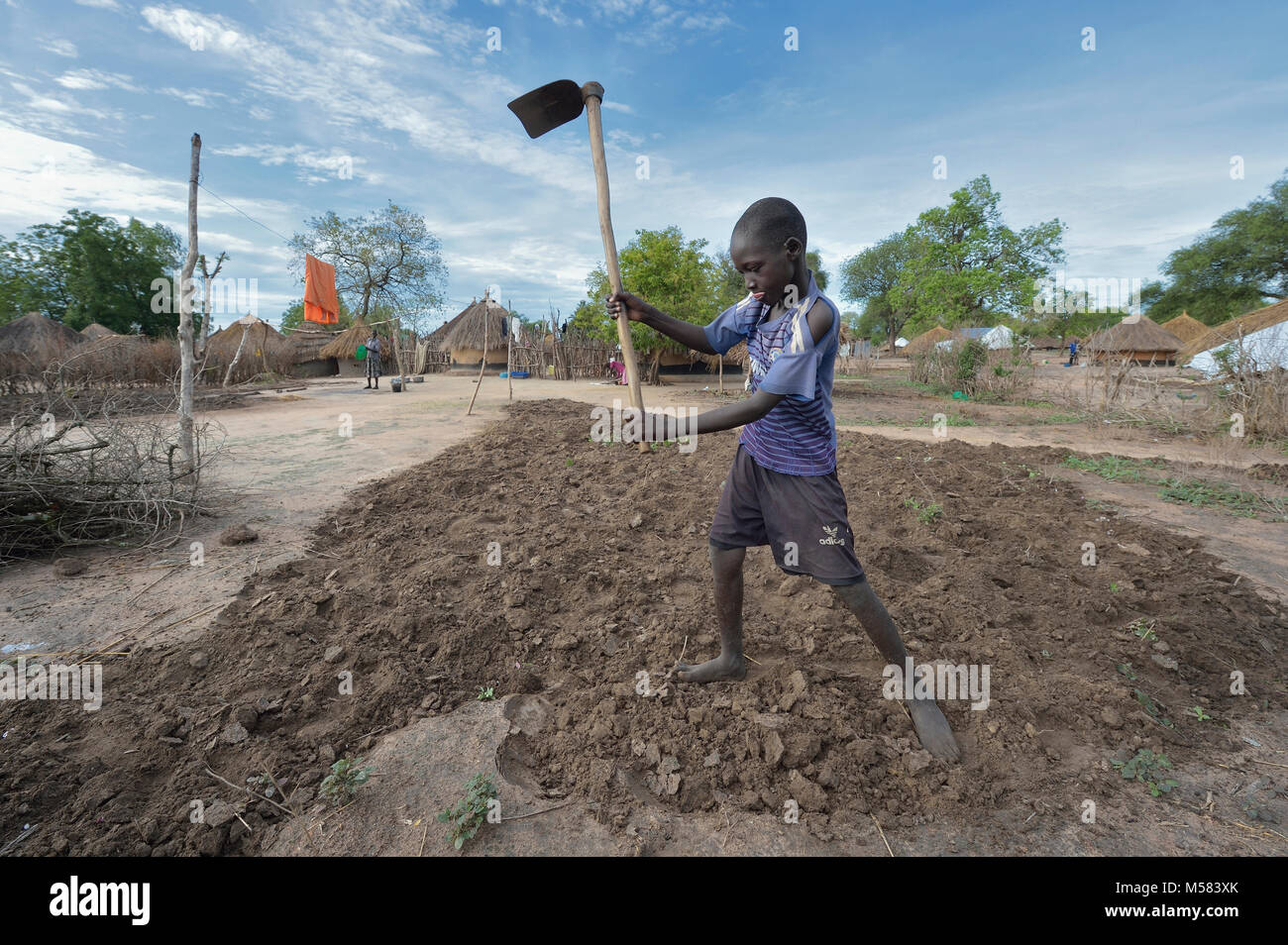 Juma Koko, 14, from South Sudan, prepares the ground for planting in the Rhino Refugee Camp in northern Uganda. Stock Photo