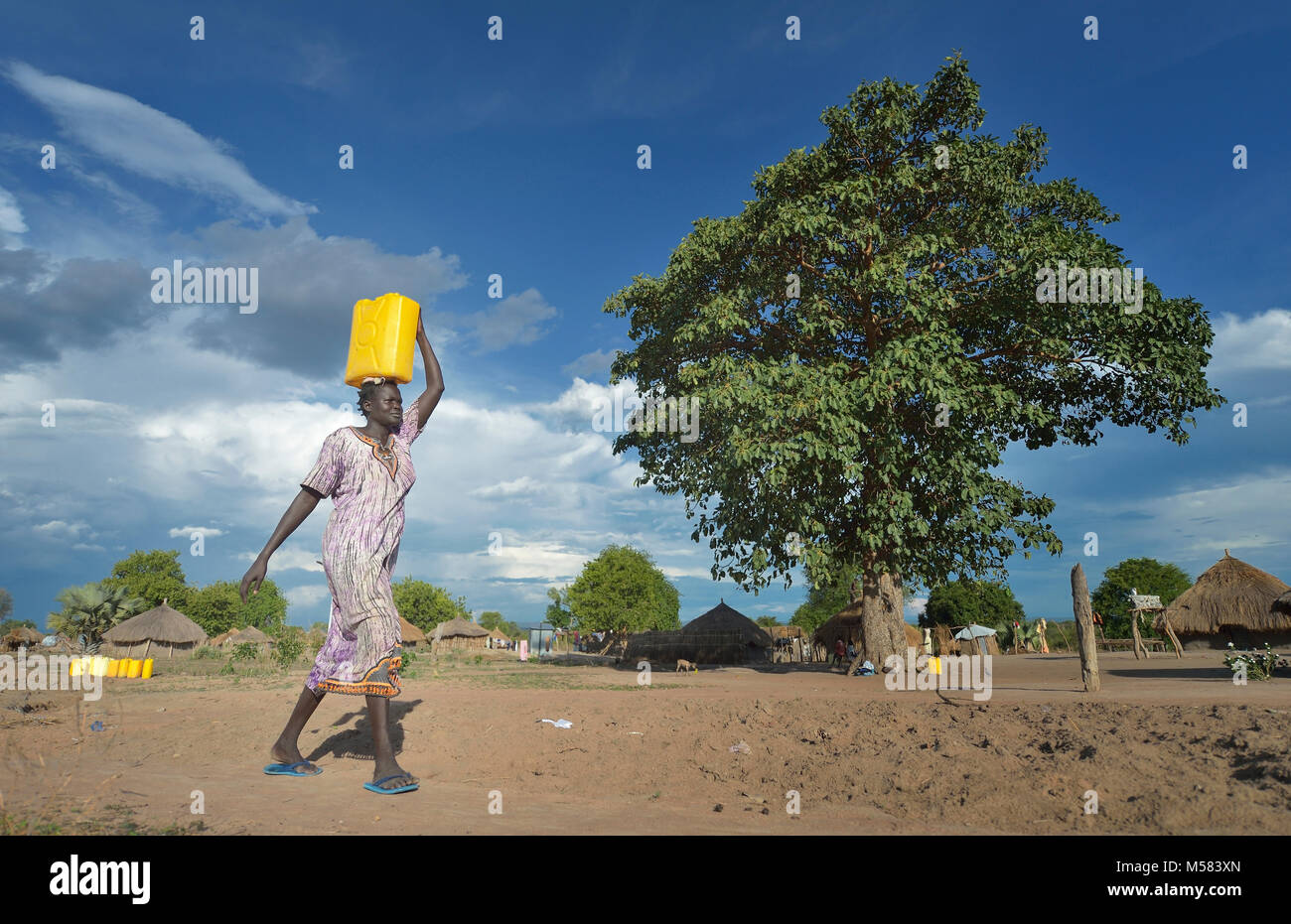 A Dinka woman from South Sudan carries water in the Rhino Refugee Camp in northern Uganda. Stock Photo