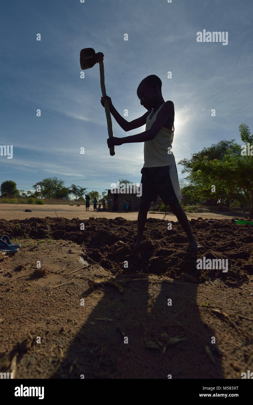 John Ankay, 13, from South Sudan, prepares the ground for planting in the Rhino Refugee Camp in northern Uganda. Stock Photo