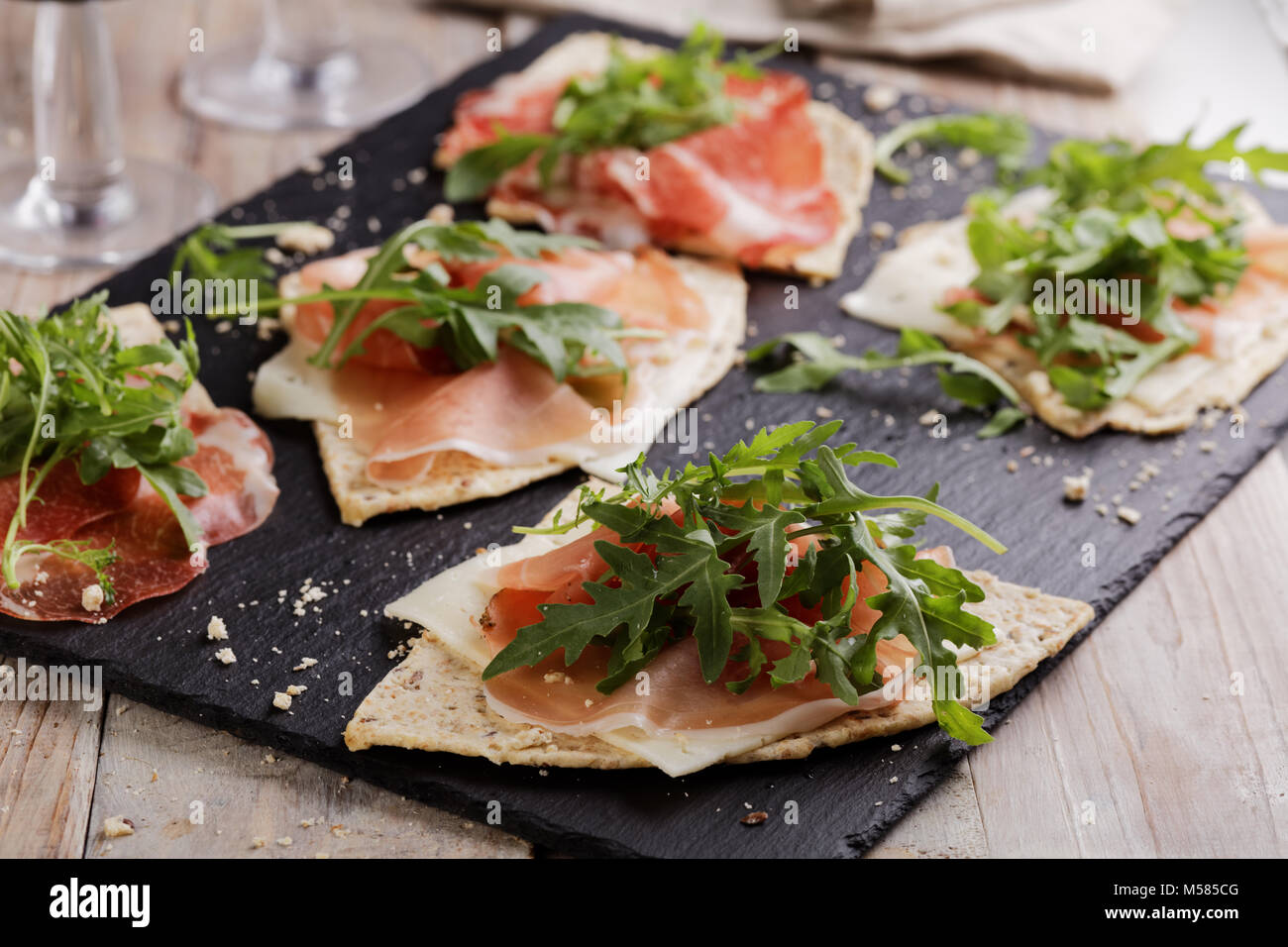 Sandwiches with Prosciutto, sliced cheese, and rocket salad on wedges of piadina Stock Photo