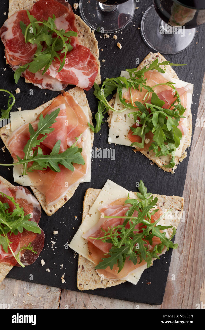 Sandwiches with Prosciutto, sliced cheese, and rocket salad on wedges of piadina Stock Photo
