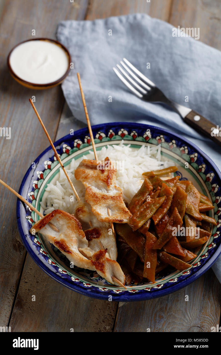Roasted chicken on sticks with rice and vegetables Stock Photo