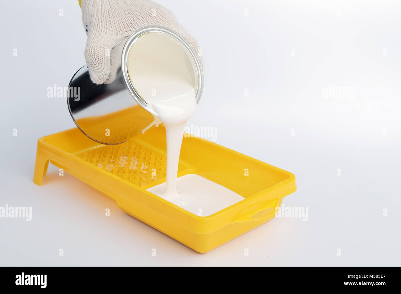 Pouring white paint into a painting tray Stock Photo Alamy