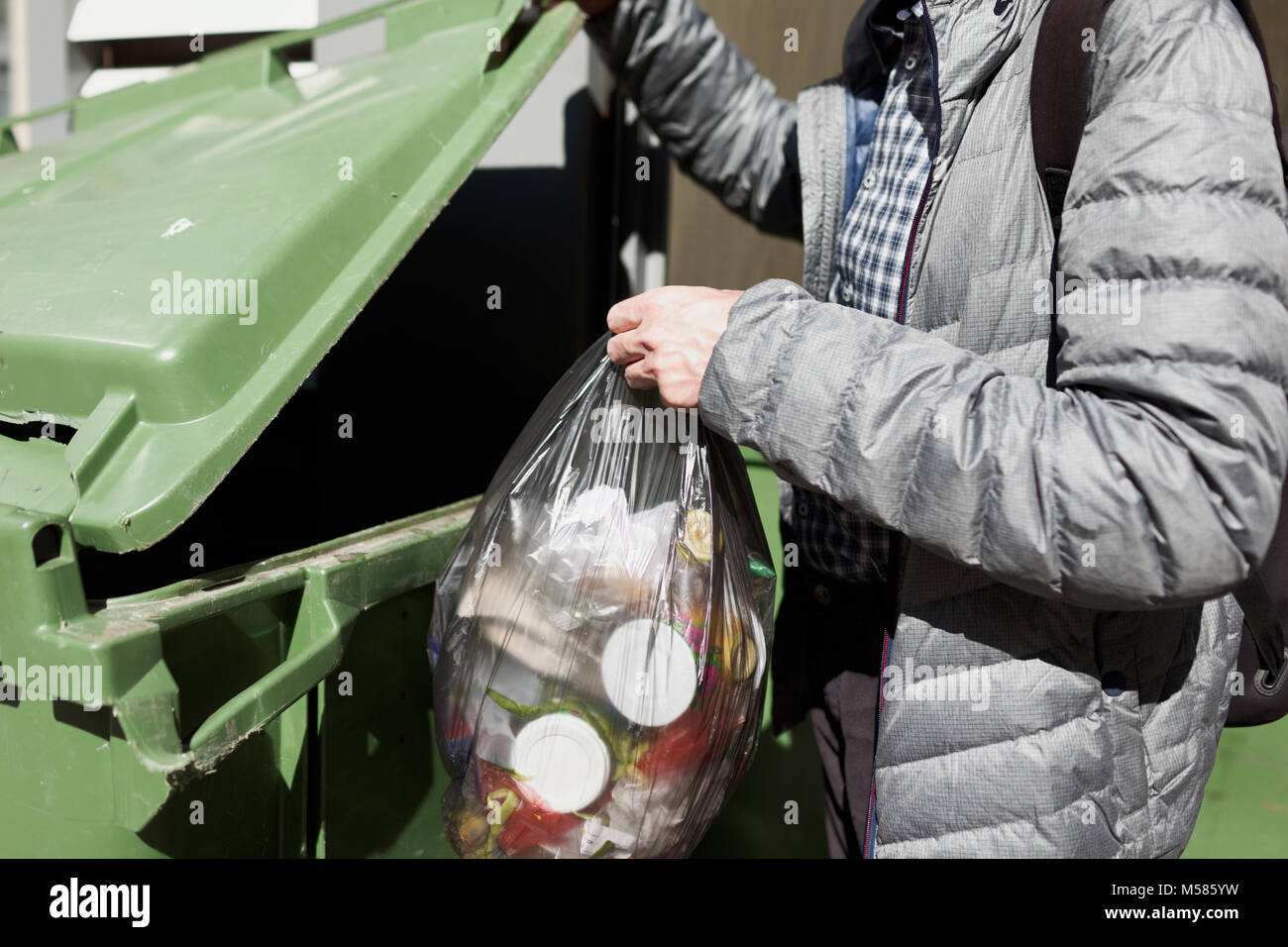 Man puts unsorted garbage in trash Stock Photo