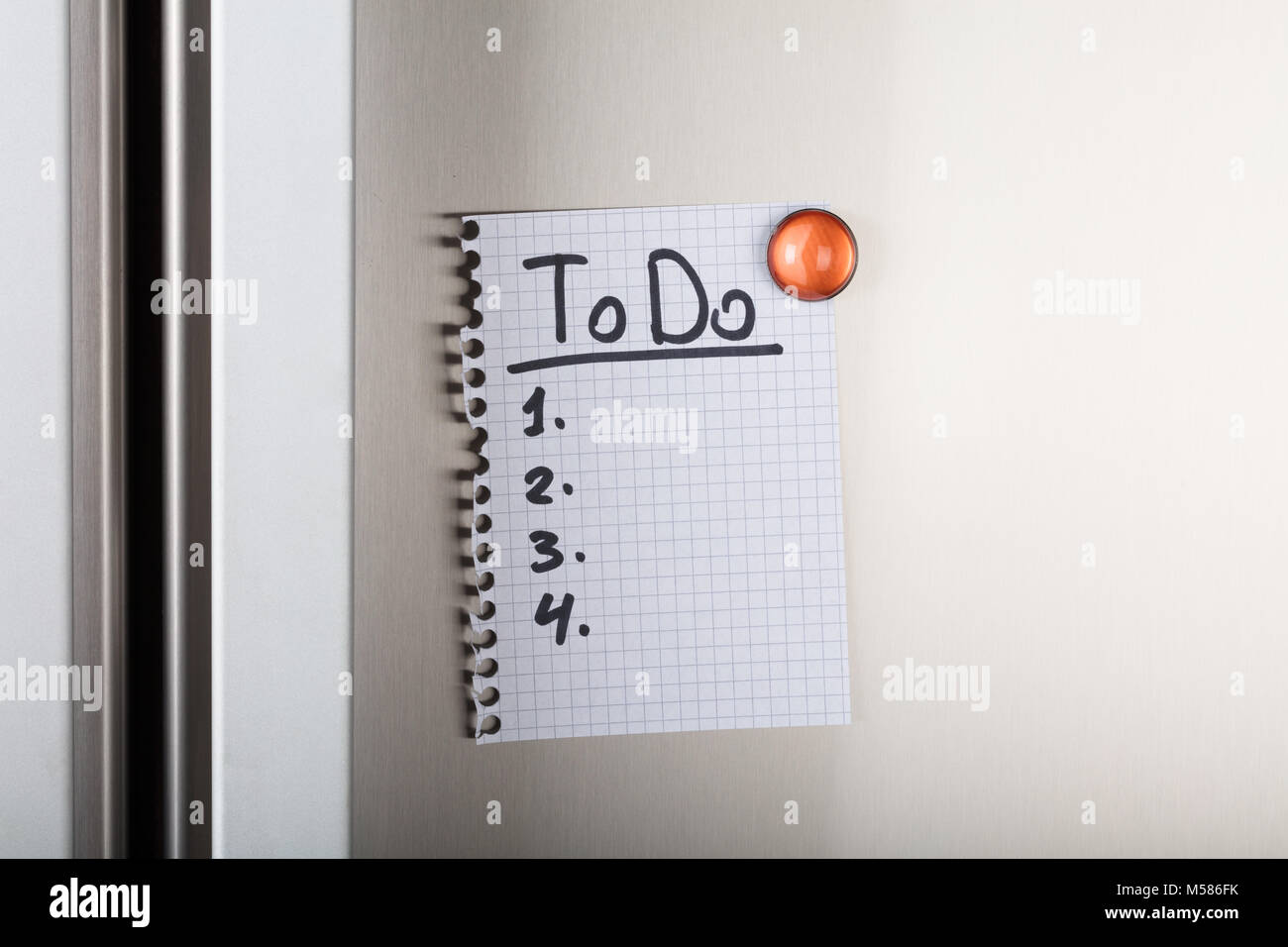 Closeup of to do list attached with orange magnetic thumbtack on metal Stock Photo