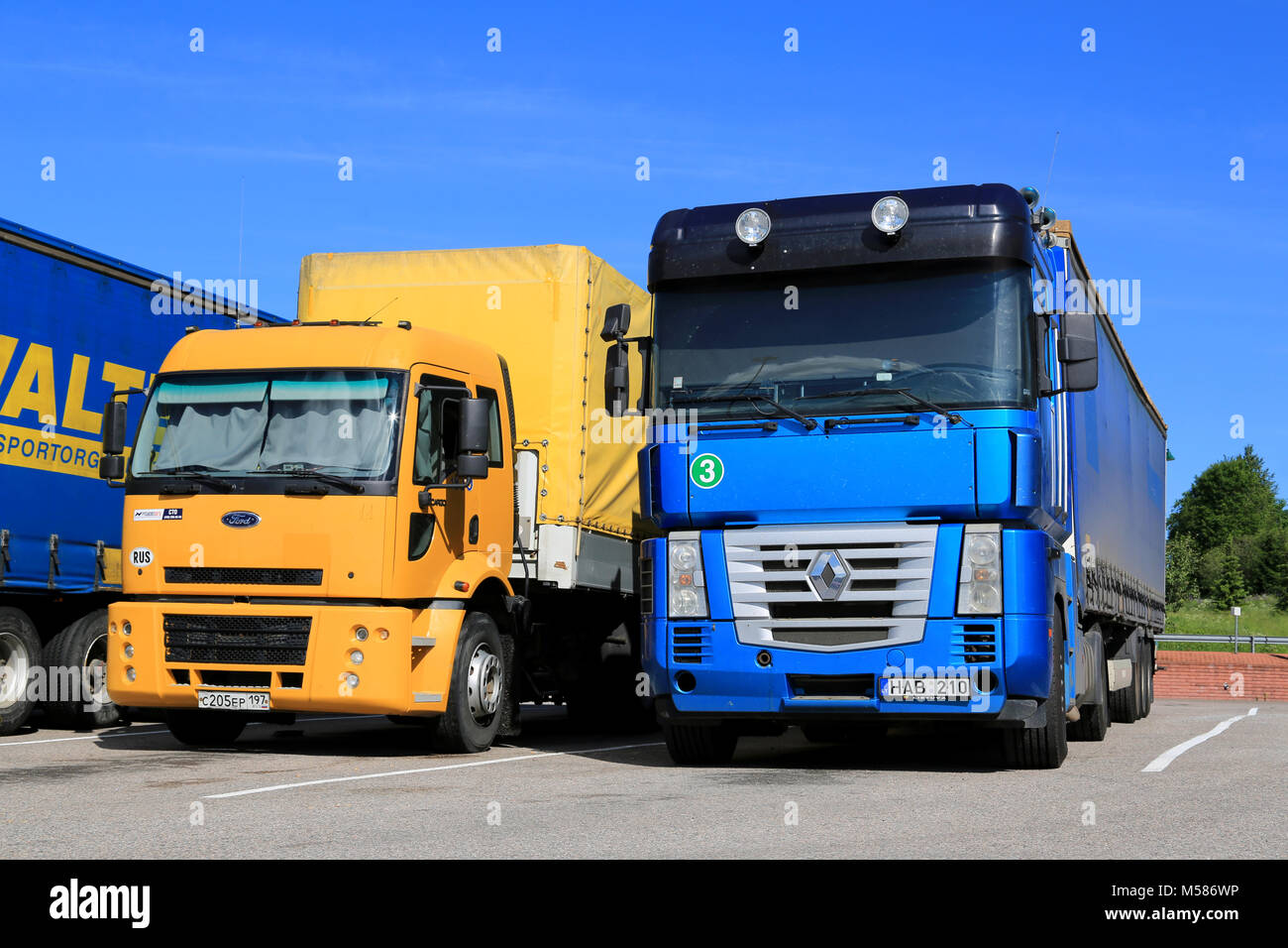 SALO, FINLAND - JUNE 15, 2014: Yellow Ford Cargo 1830 and blue Renault Magnum semi trucks parked. Ford Cargo was launched in 1981, and Renault Magnum  Stock Photo