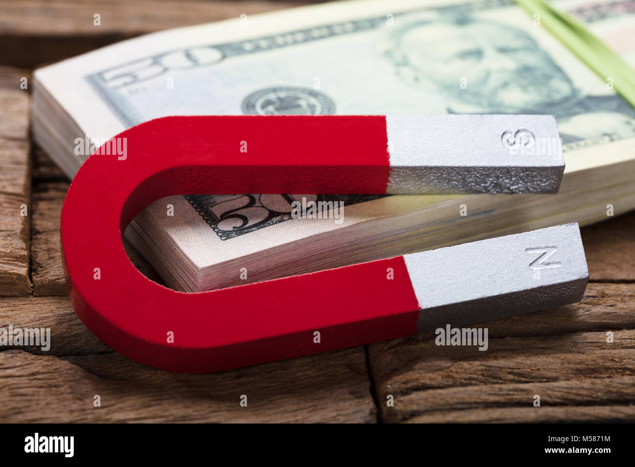 Closeup of magnet and 50 dollar bill bundle on wooden table Stock Photo