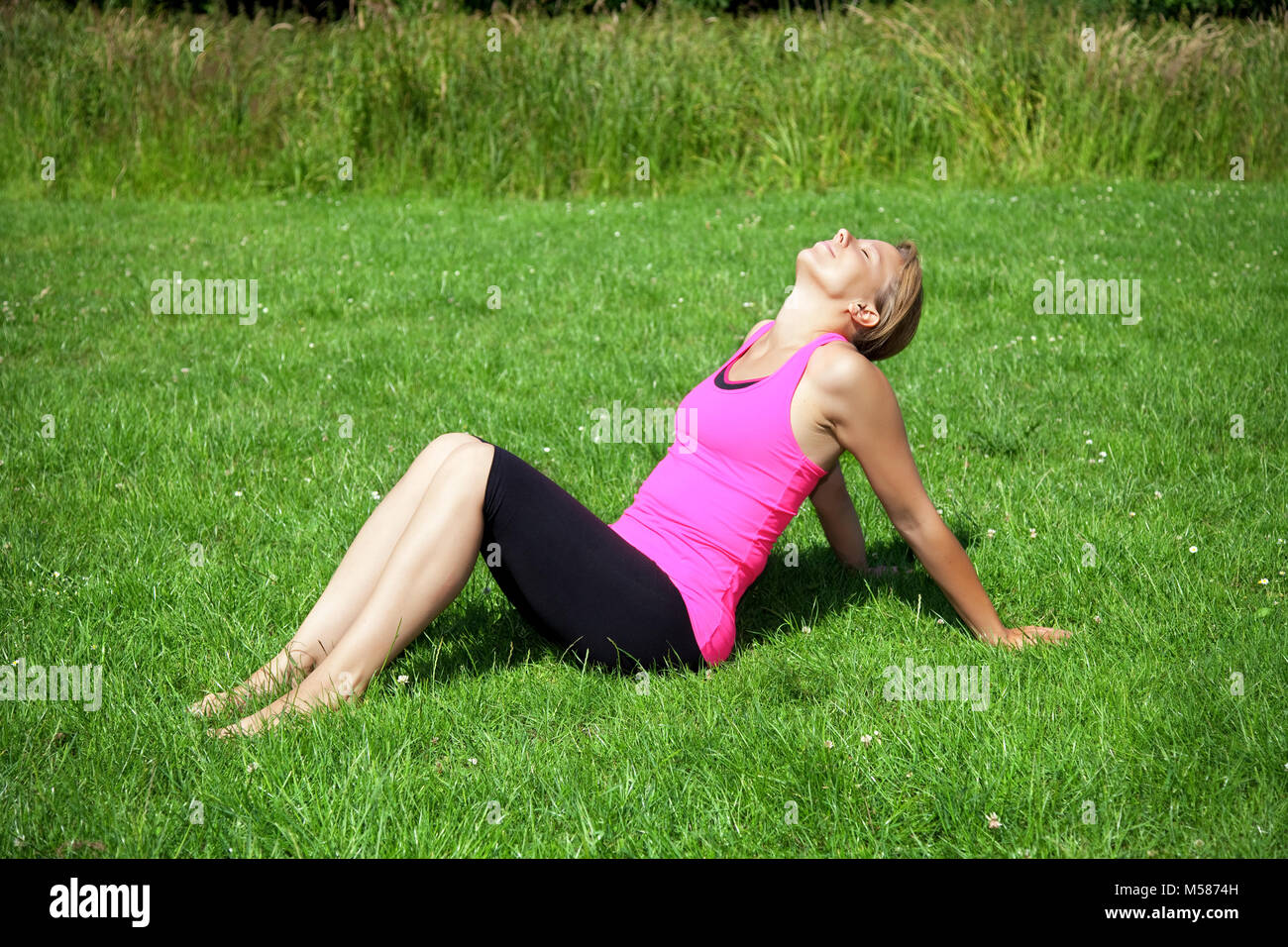 young fitness woman sitting on green grass Stock Photo