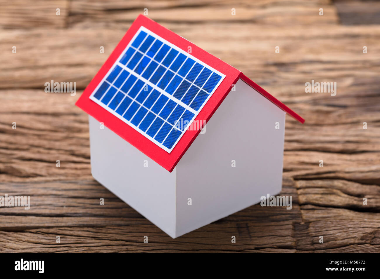Closeup of solar panel on model home at wooden table Stock Photo