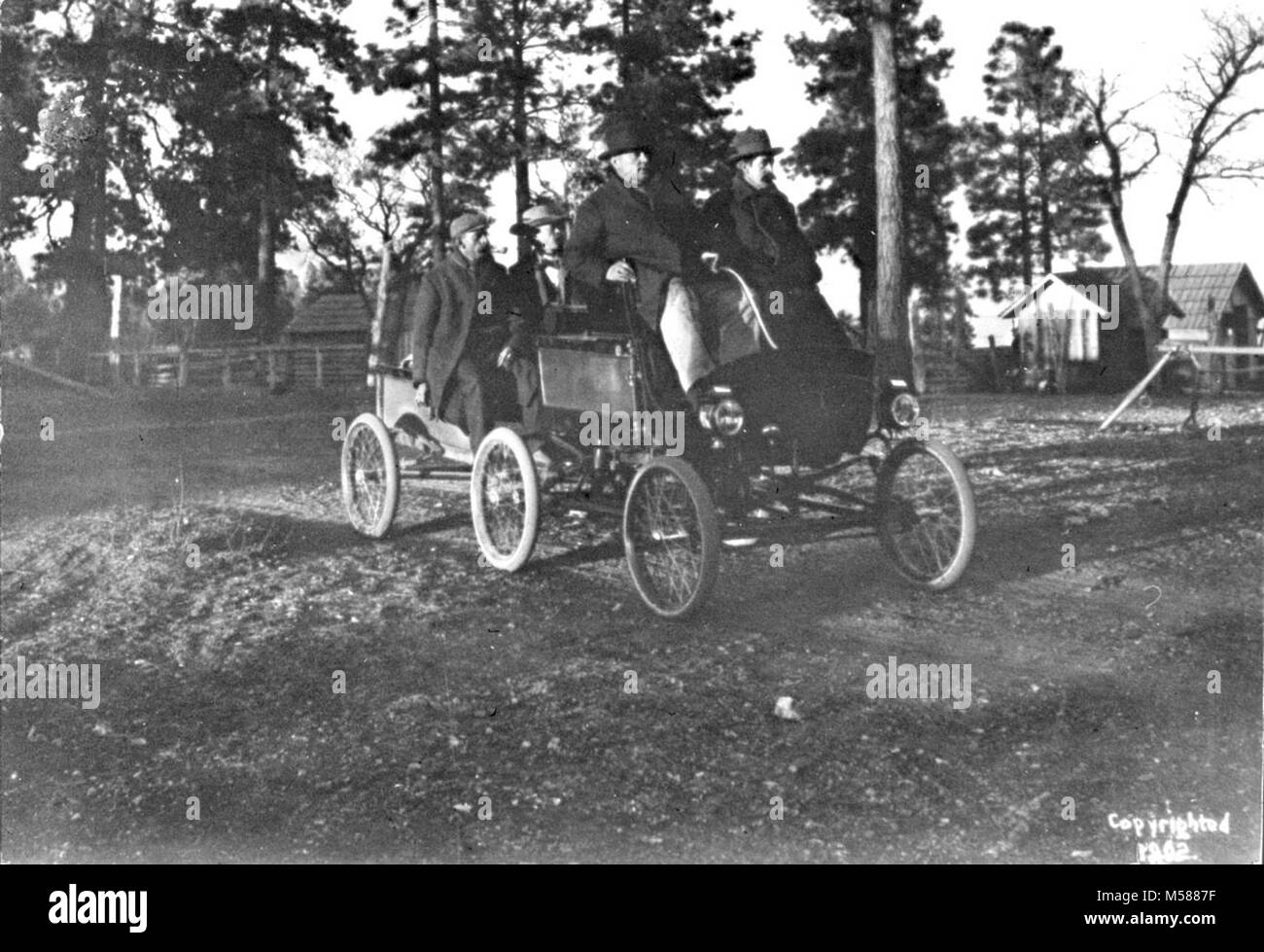 Grand Canyon National Park First Automobile. Early January, 1902. The first automobile party arrives at Grandview, on the South Rim of Grand Canyon in a ten horse-power steam powered vehicle.  Oliver Lippincott is the driver (they called it “steerer”) with Thomas Chapman sitting in the front seat beside the Lippincott.  Allen Doyle is shown riding on the trailer, with W. Hogaboom (pipe in mouth.) Stock Photo