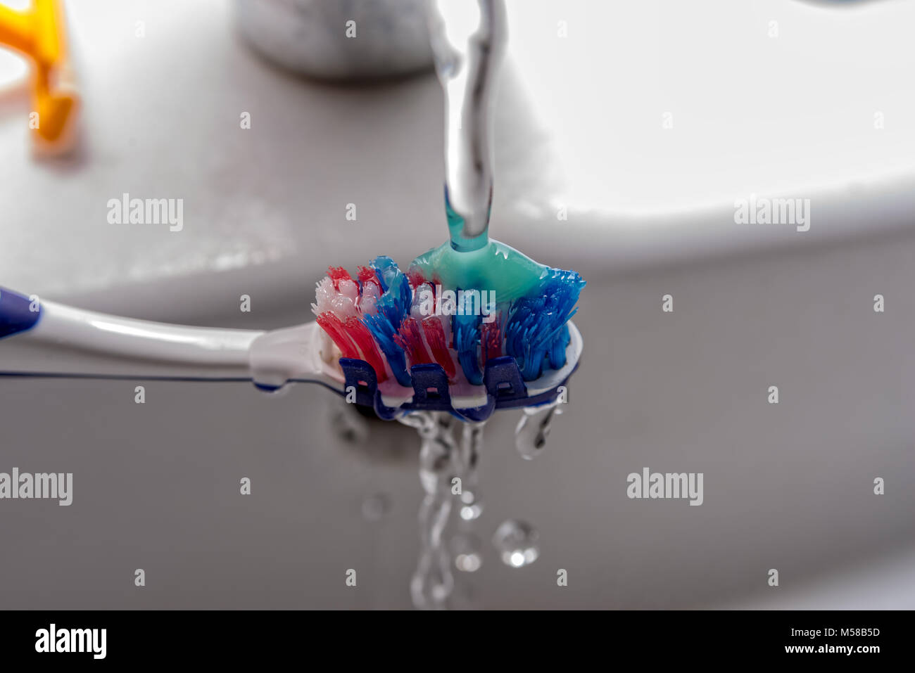 Toothbrush with toothpaste and water from the faucet Stock Photo