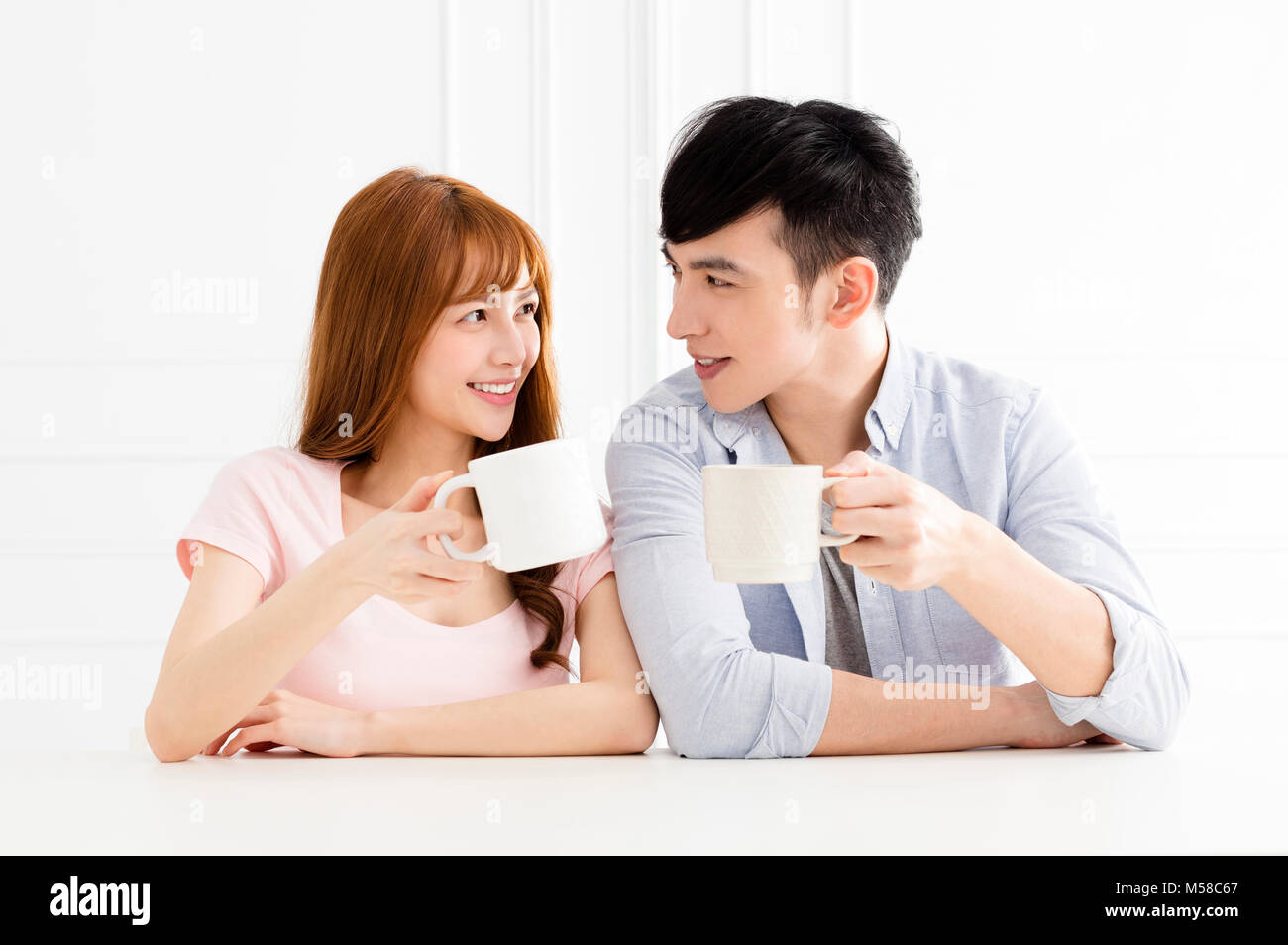 young asian couple drinking coffee in living room Stock Photo