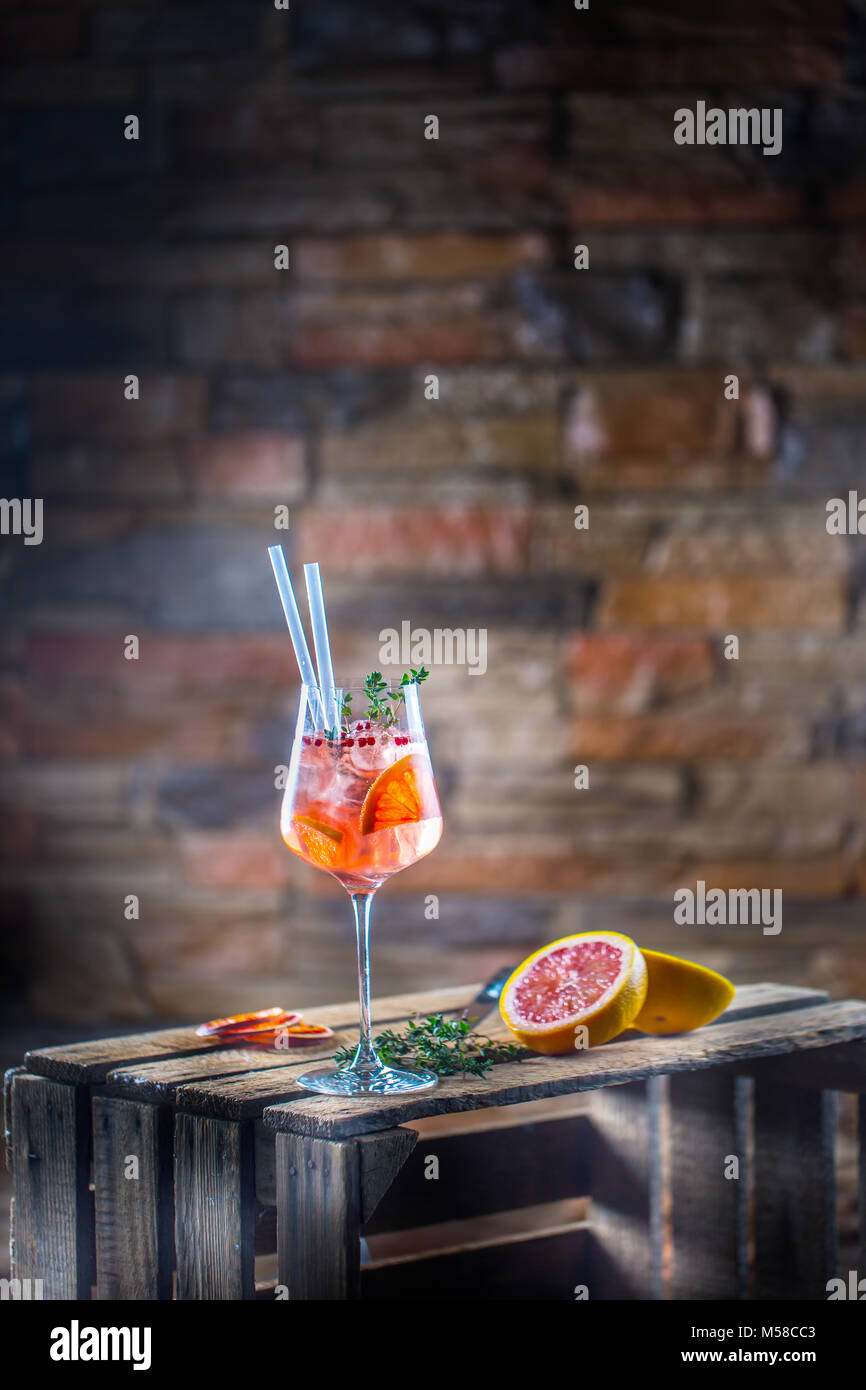 Cocktail drink on a old  wooden board. Alcoholic beverage with tropical fruits red pepper herb and ice. Stock Photo