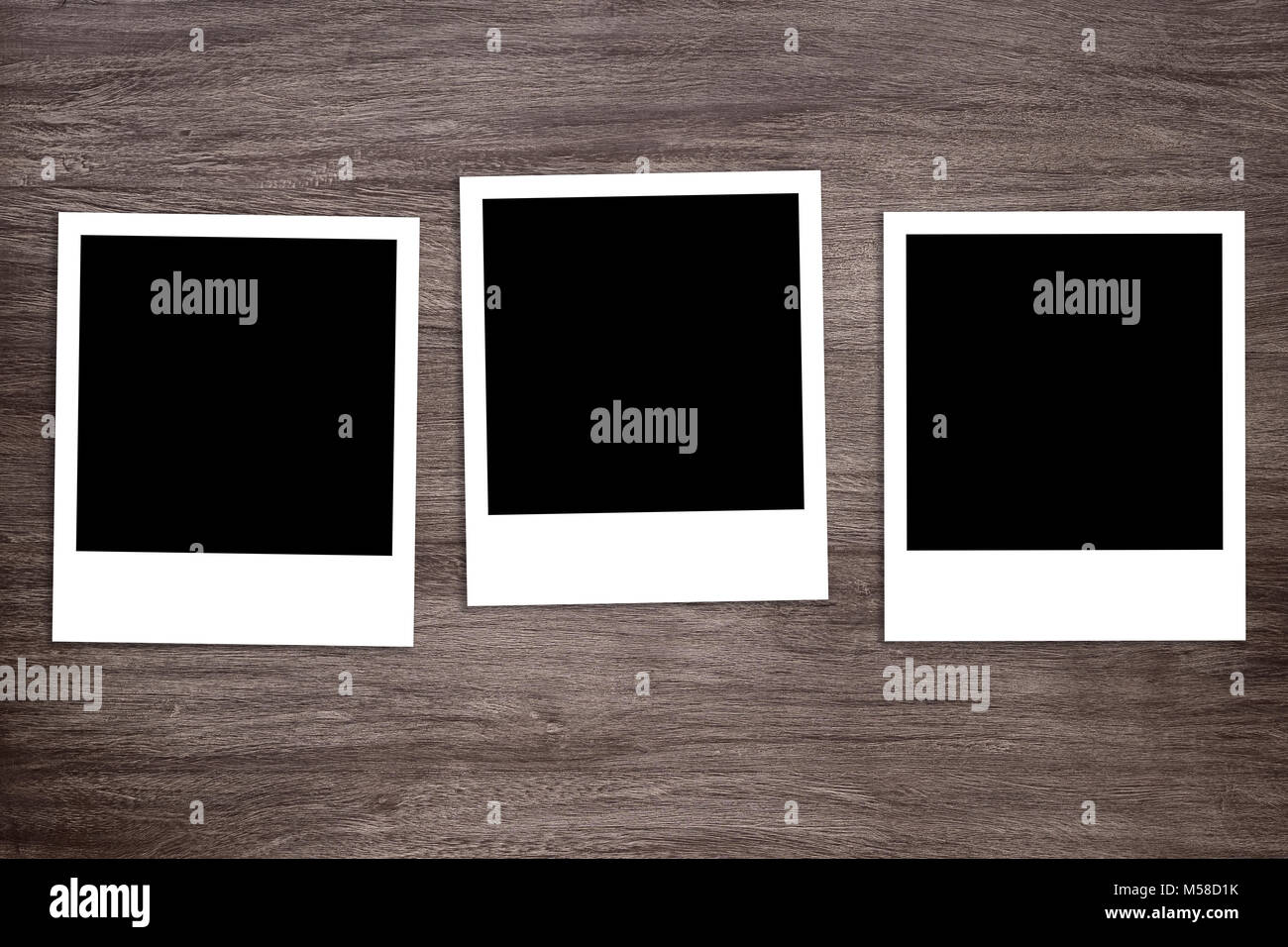 three blacked-out instant photo print templates on wooden background Stock Photo