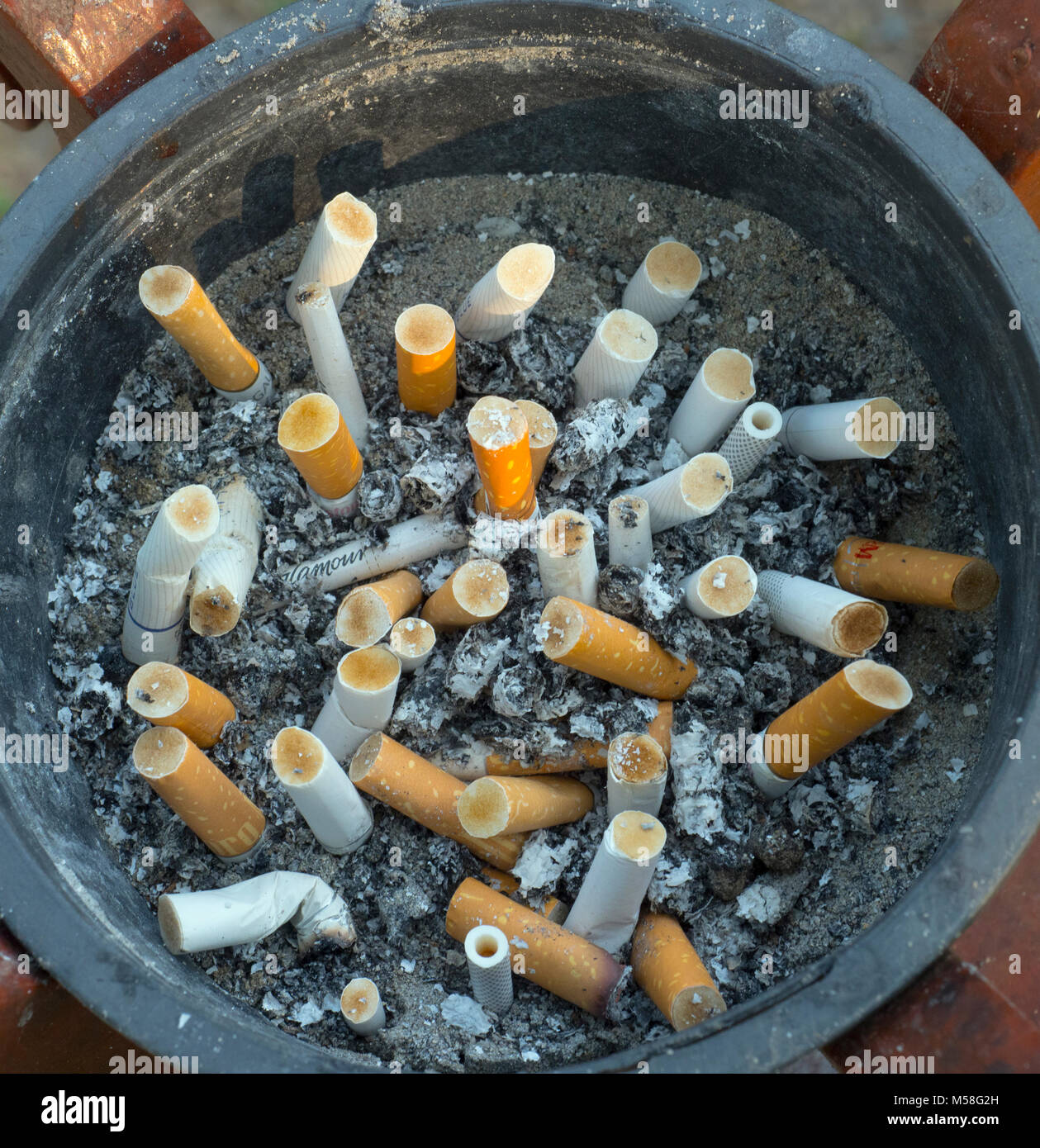 cigarette ends in ash tray in hotel smoking area Stock Photo
