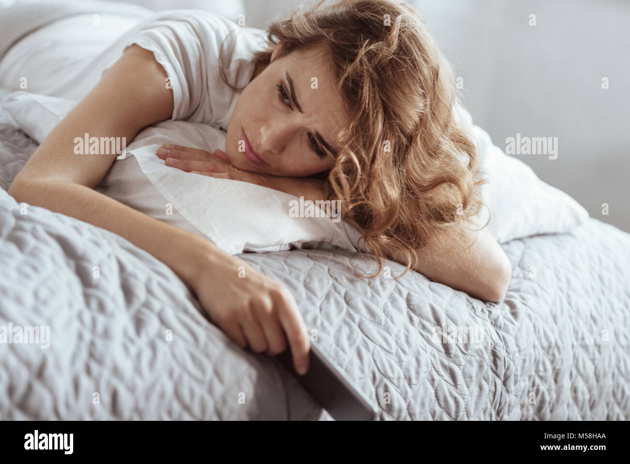 Depressed woman having negative thoughts while lying on bed Stock Photo