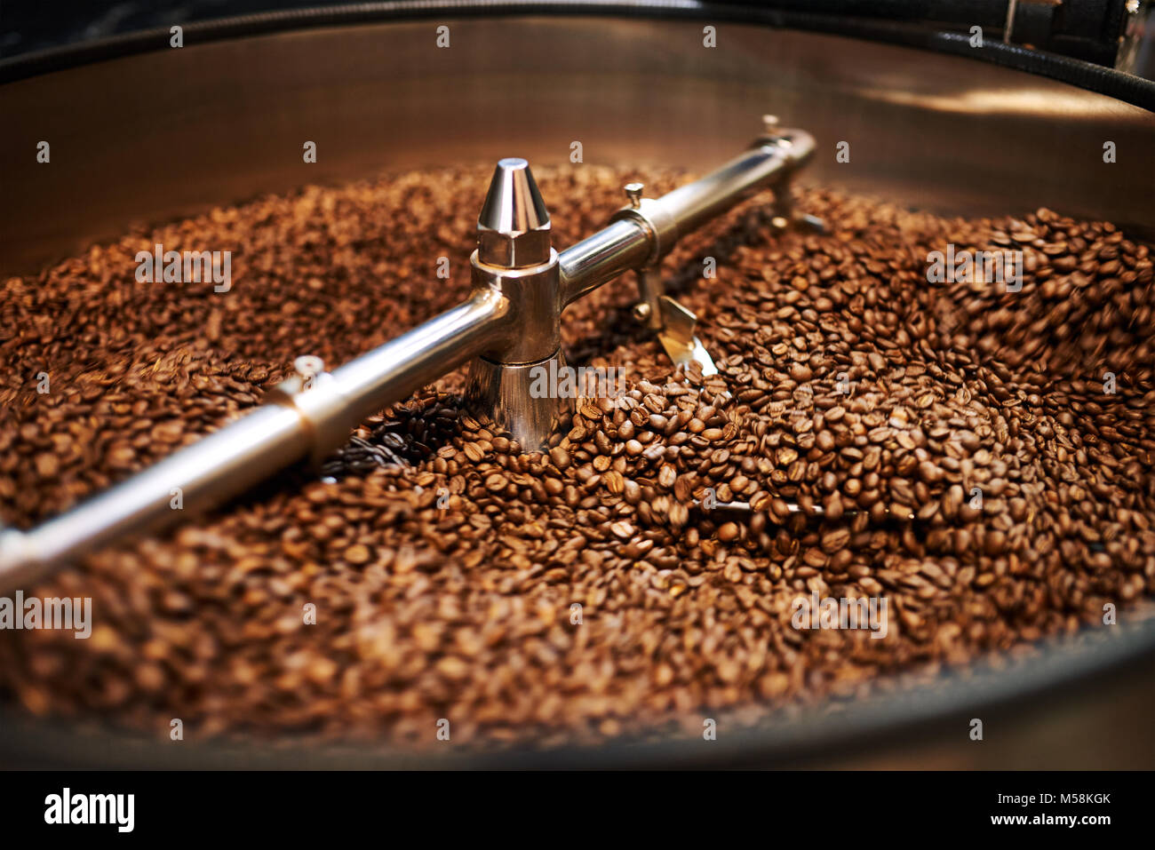 Stainless steel arms mixing freshly roasted coffee beans in large stainless steel cooling drum where the beans are cooled down before packaging or sto Stock Photo