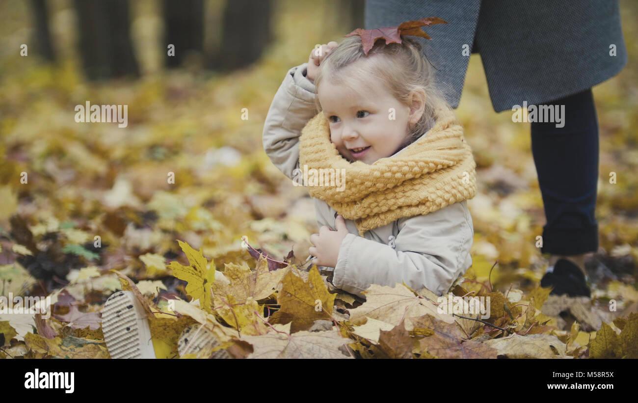 Little blonde baby girl plays with leaves in autumn park Stock Photo ...