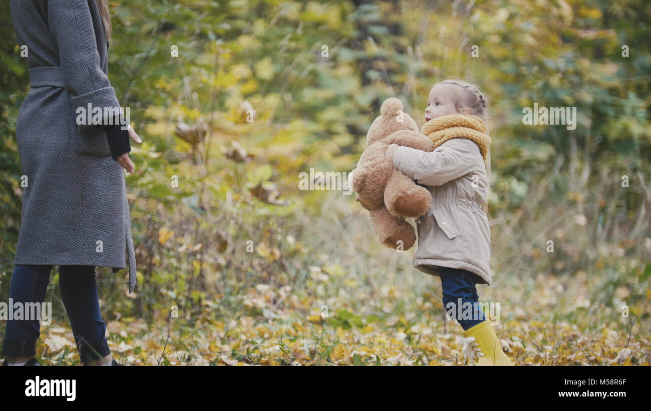 Pretty blonde little girl in autumn park plays with teddy bear Stock ...