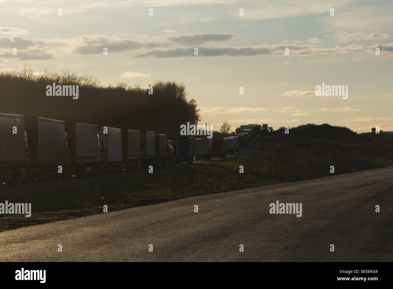 Traffic Jam of Heavy Trucks at Sunset - wide angle Stock Photo