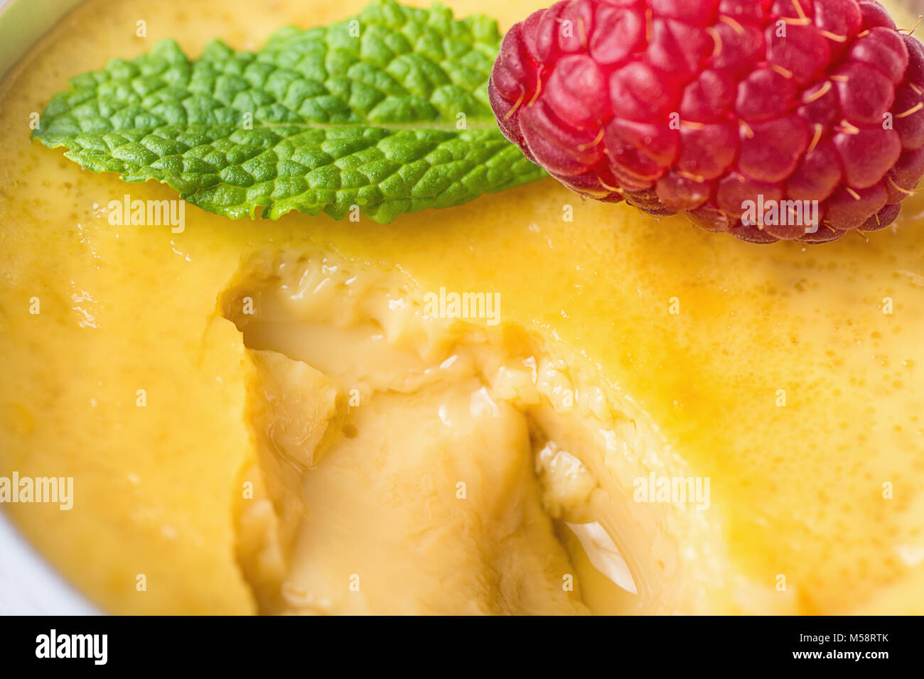 Sweet Vanilla Egg Custard Cream Flan with Fresh Raspberry and Mint in Portion Cup Scooped. Macro Food Photography. Visible Creamy Texture and Caramel  Stock Photo