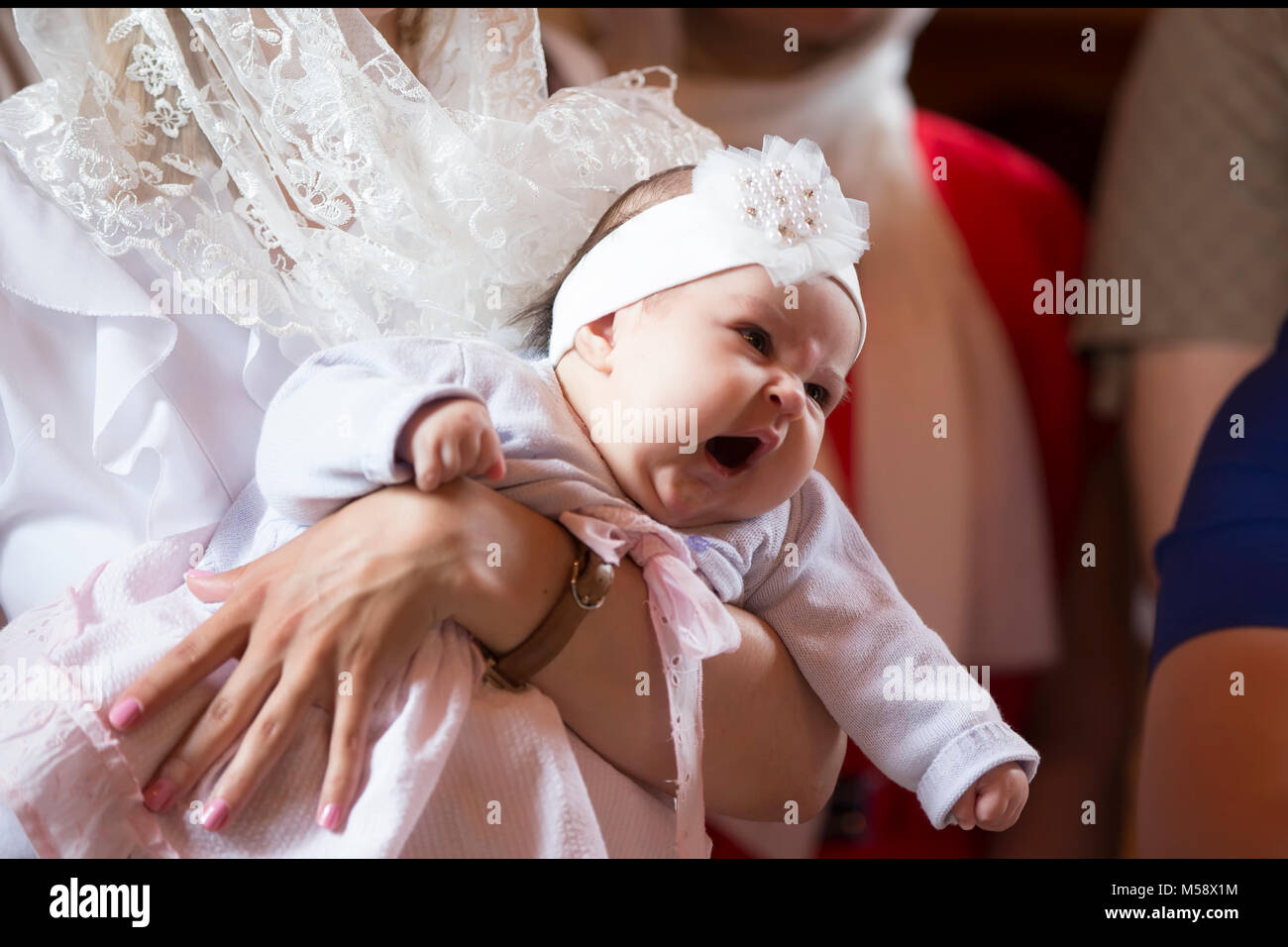 Belarus, the city of Gomel. June 10, 2017. Church at the regional hospital. The baptism of a child.A baby child yawns in his arms at the rite of bapti Stock Photo