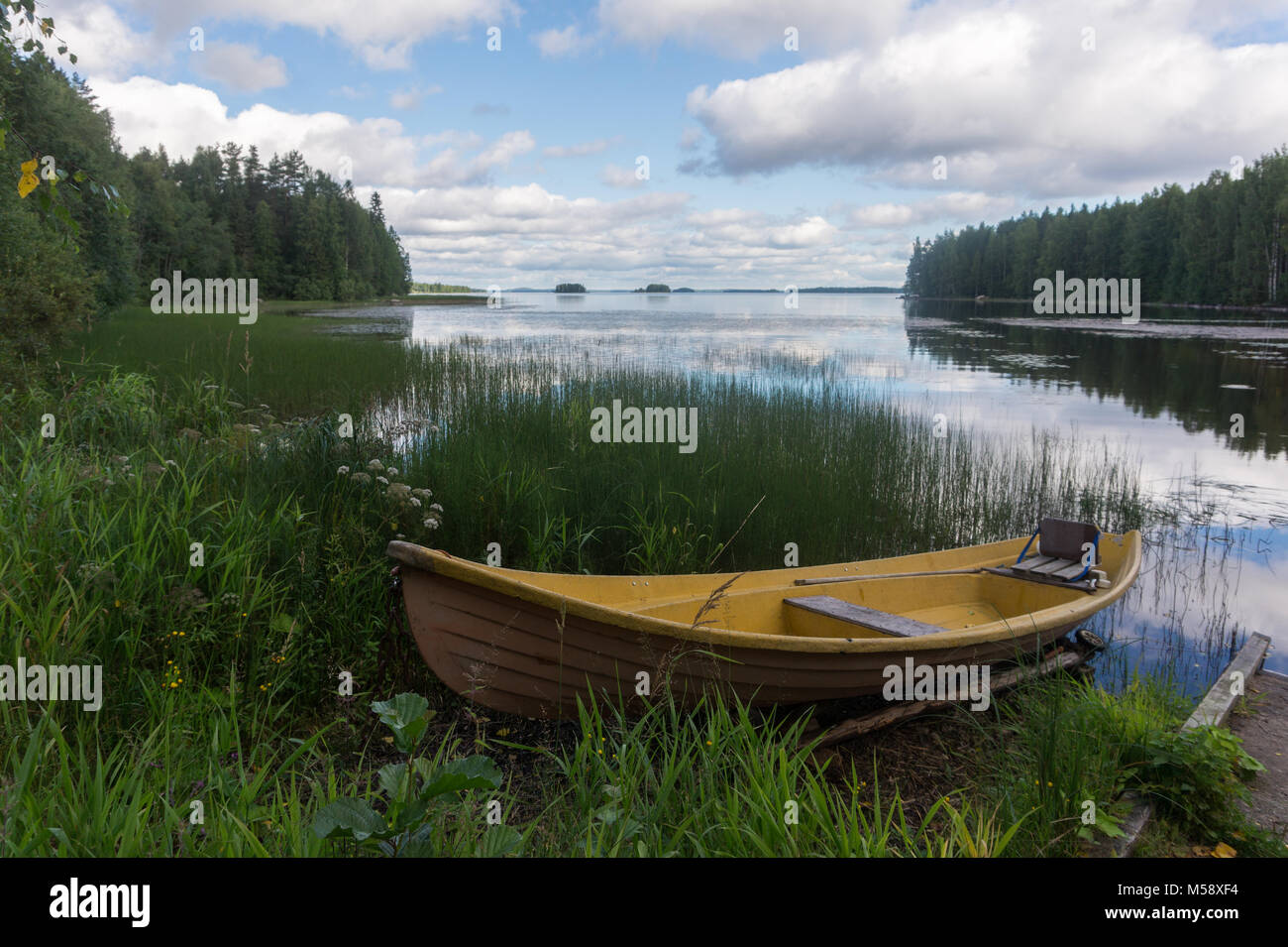 Yellow wooden boat on the shore of a picturesque lake and a reflection ...