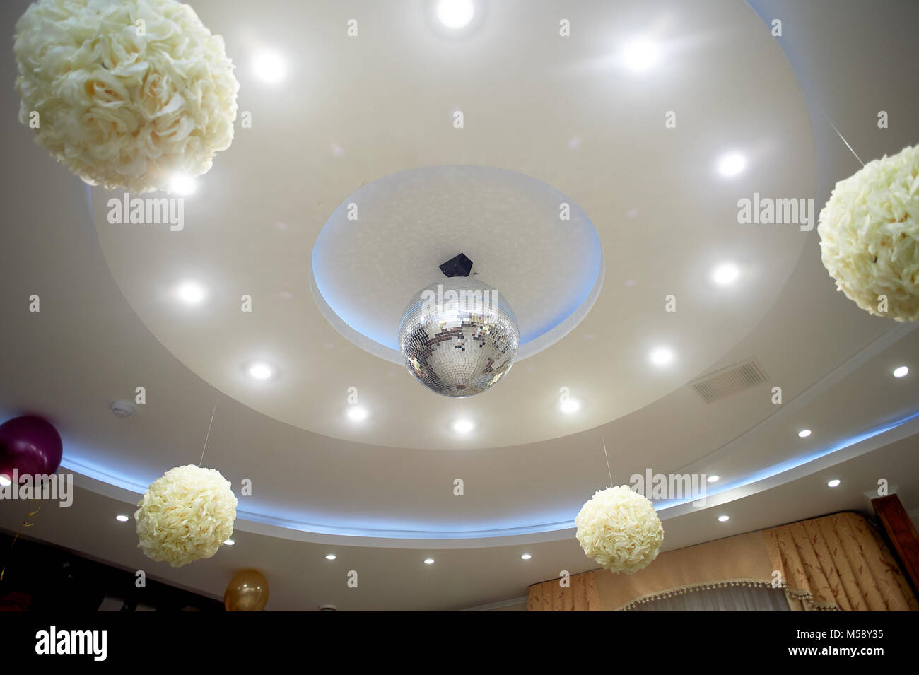 The high white ceiling with exposed beams. Decorated with disco balls