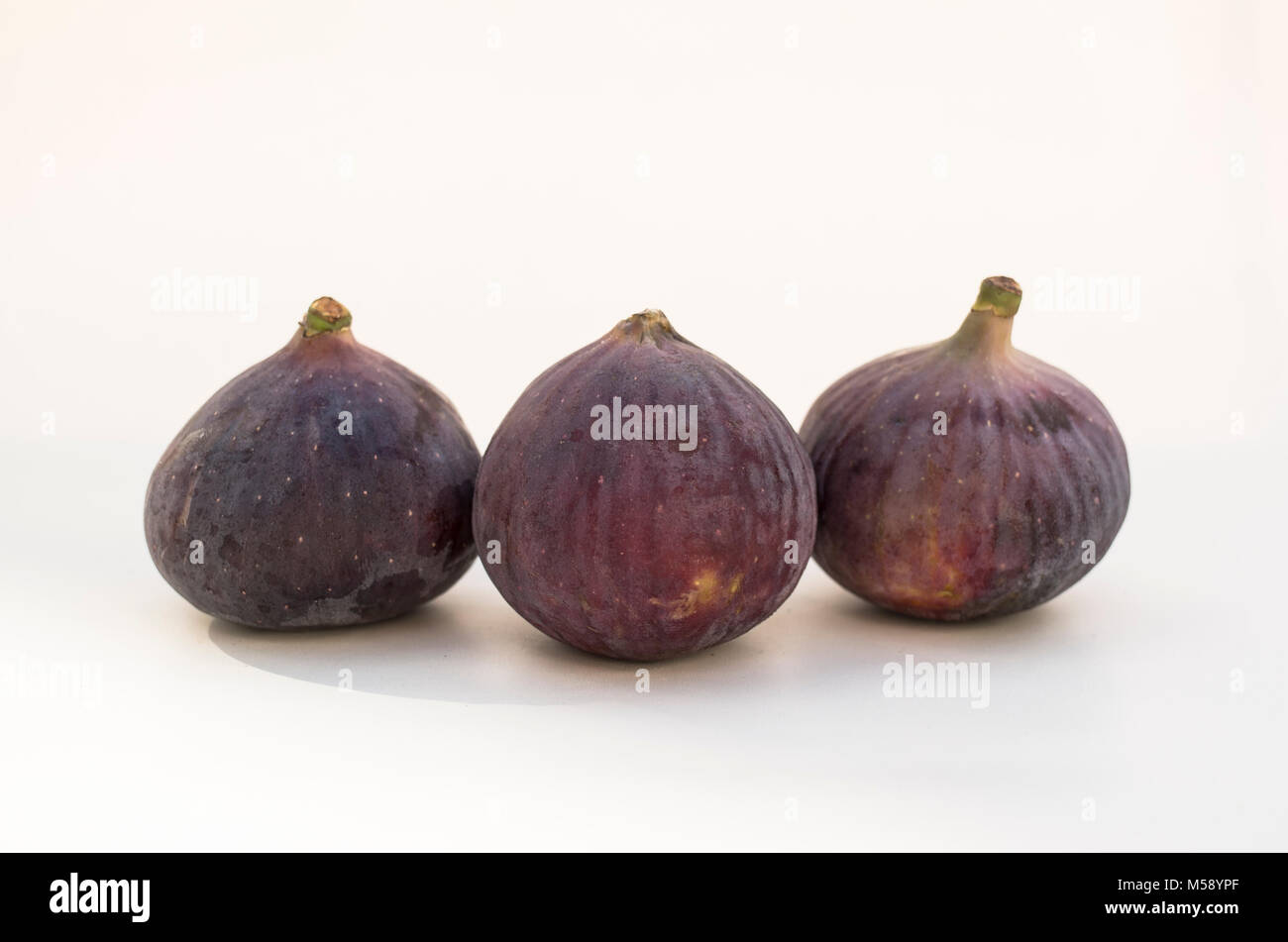 Three fresh Black Bursa ripe figs, one halved to show inside flesh and seeds Stock Photo Alamy