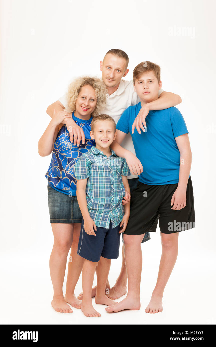 Full body portrait of a young family with father, mother and two boys in front of white background. Stock Photo