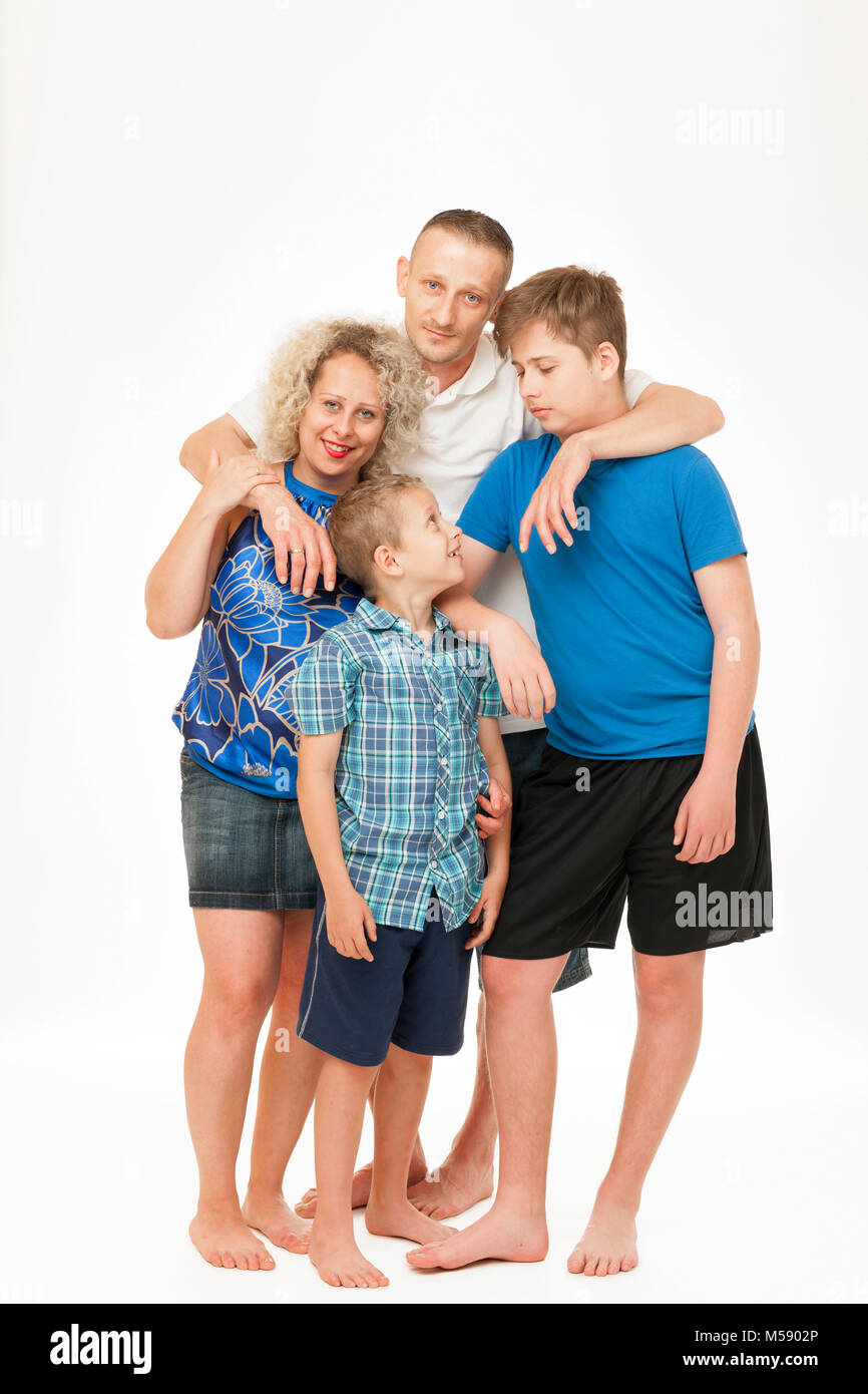 Full body portraits of a young standing family with father, mother and two boys against white background. Stock Photo