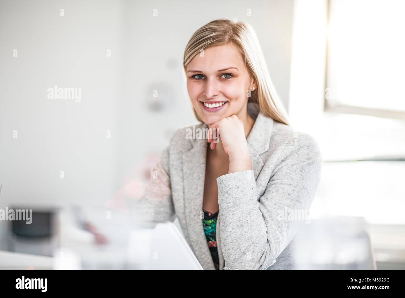 Portrait of confident young businesswoman with hand on chin in office Stock Photo