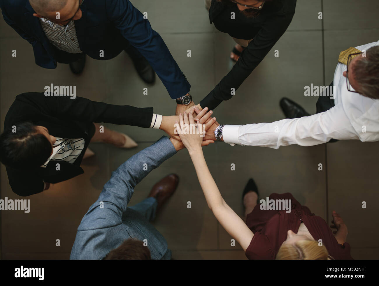 Business team putting hands together at the office. Top view of diverse