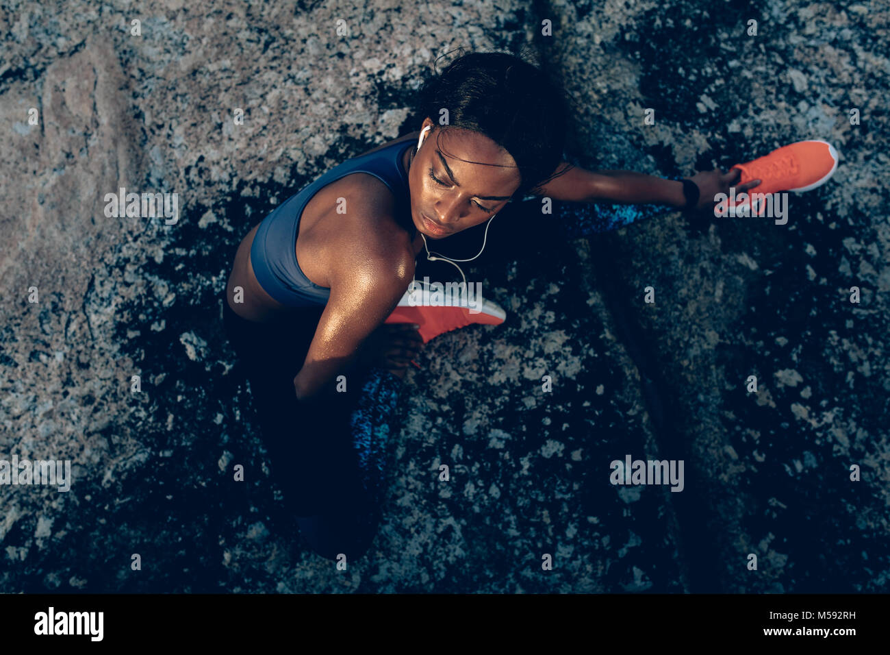 Top view of fit young woman sitting over rocks after workout session ...